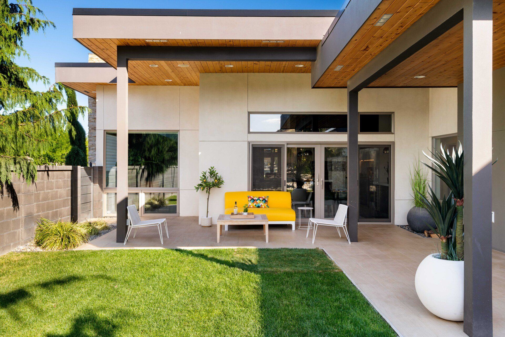The backyard of a house with a yellow couch and chairs
