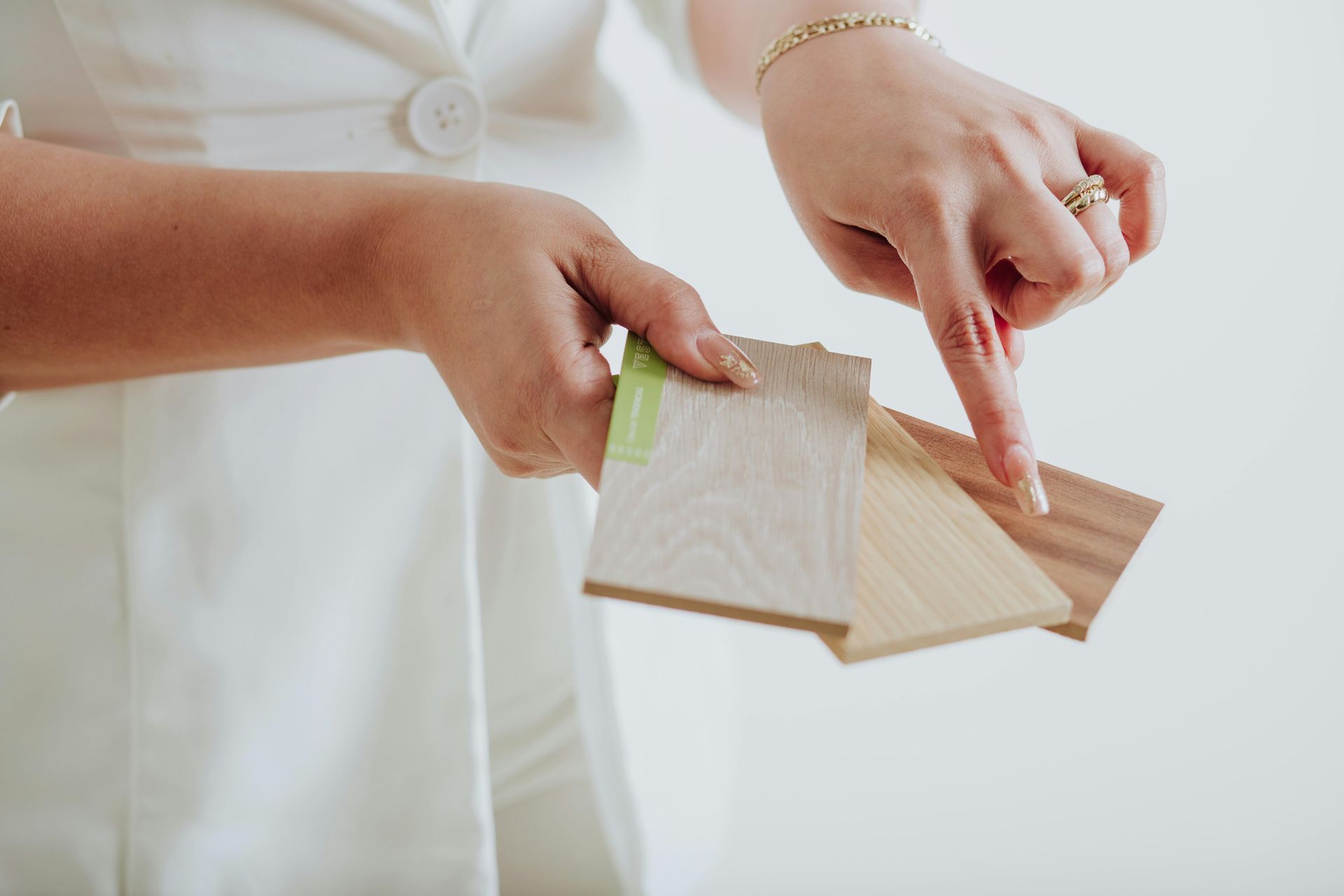 Person holding and pointing at wood flooring samples.
