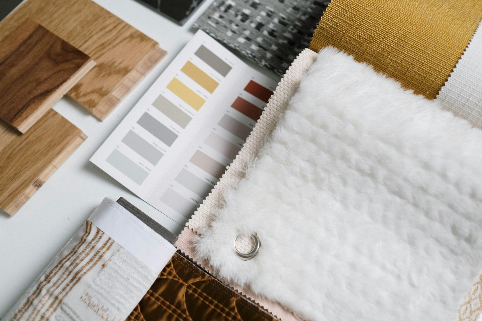 Samples of wood, fabric swatches, and a paint color palette displayed on a white surface.