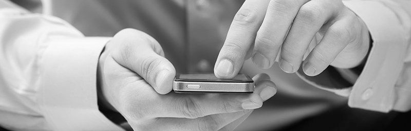 Auf einem Schwarzweißfoto benutzt eine Person ein Mobiltelefon.