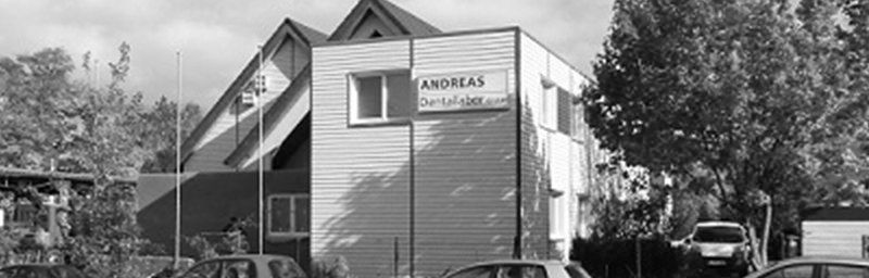 Ein Schwarzweißfoto eines Gebäudes mit davor geparkten Autos.