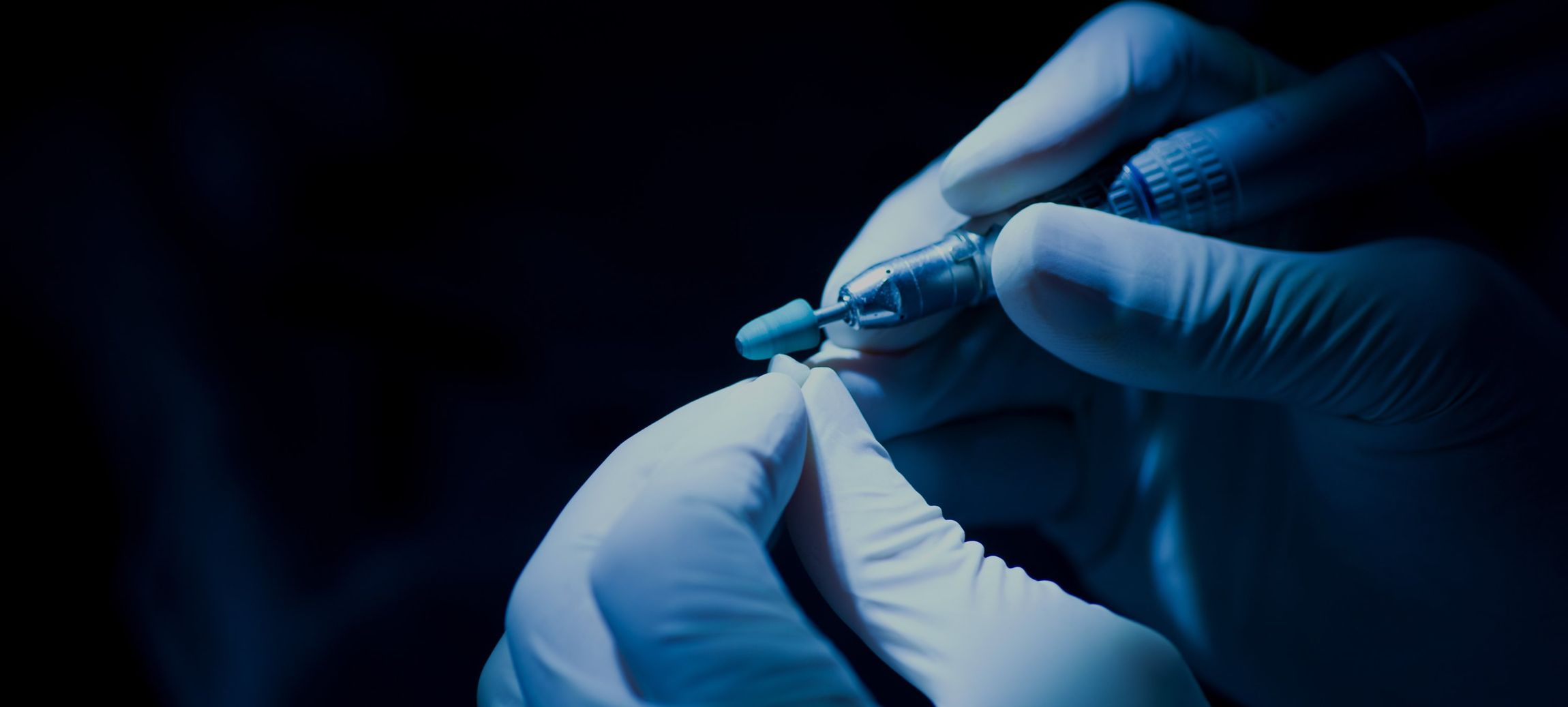 Eine Person mit Handschuhen hält eine Nadel in der Hand.
