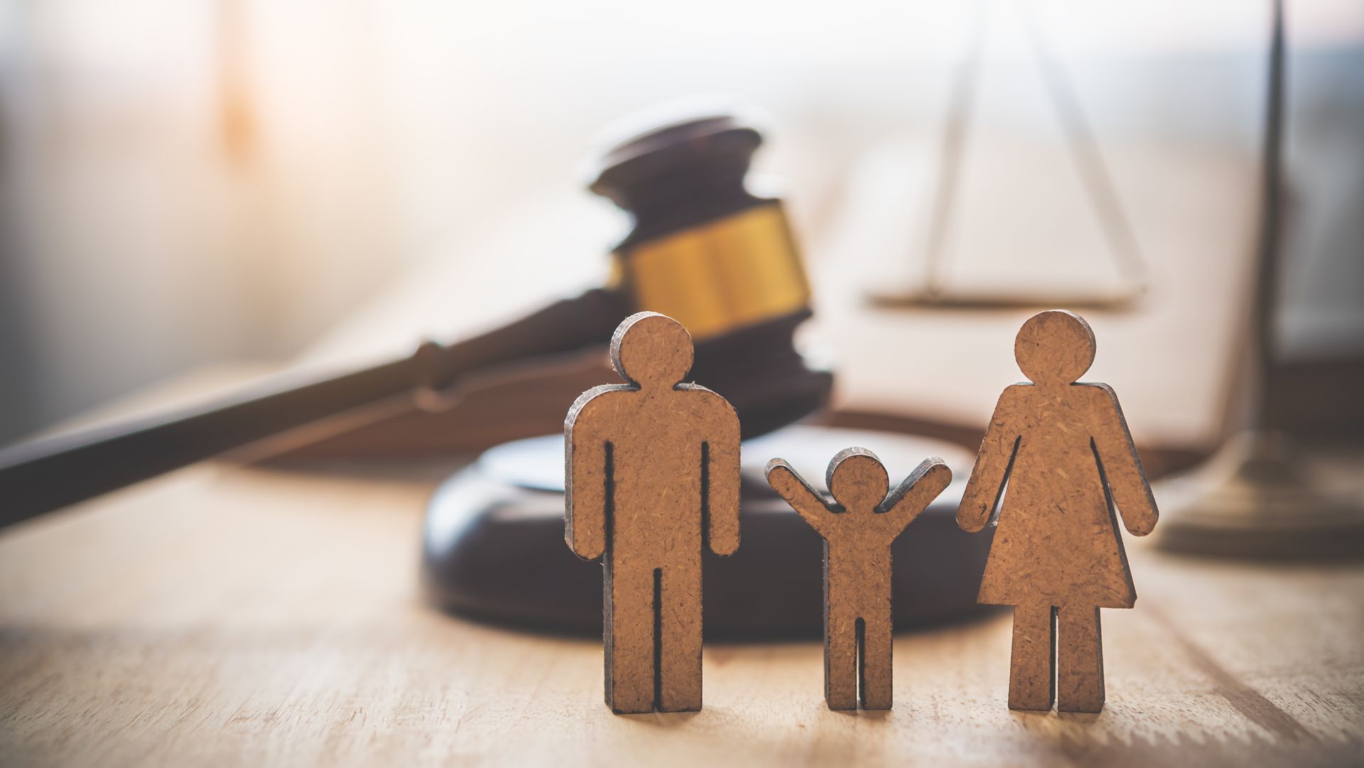 Wooden cutouts of a family with two adults and one child standing on a wooden surface. Wooden cutouts of a family with two adults and one child standing on a wooden surface.