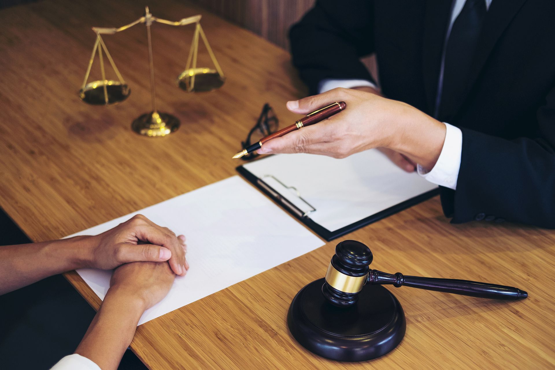 Lawyer consulting client with legal documents, gavel and scales of justice on desk. Lawyer consulting client with legal documents, gavel and scales of justice on desk.