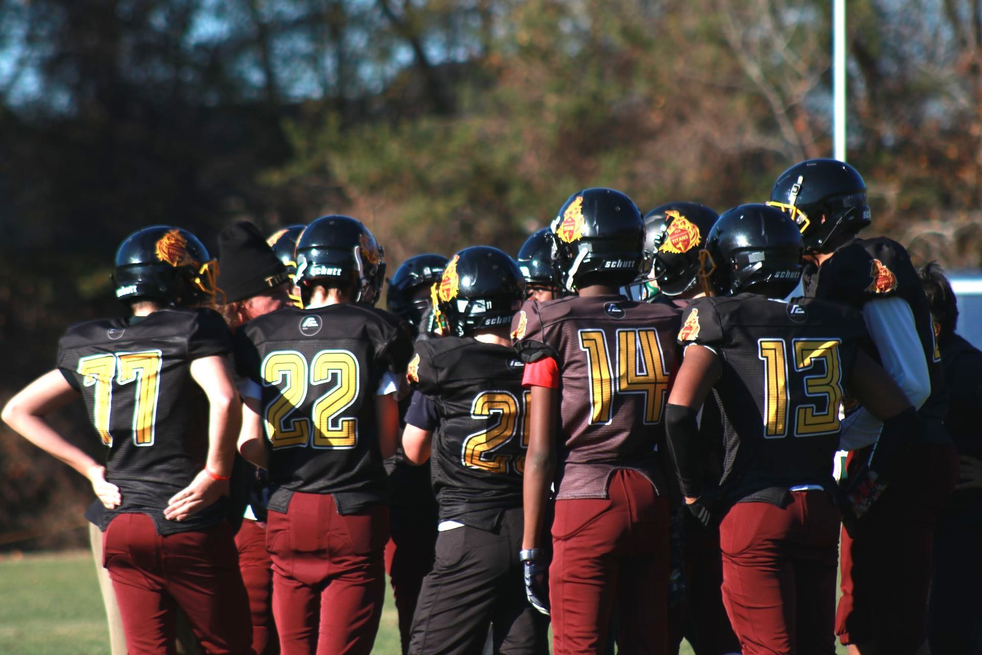 13 U football players in huddle.