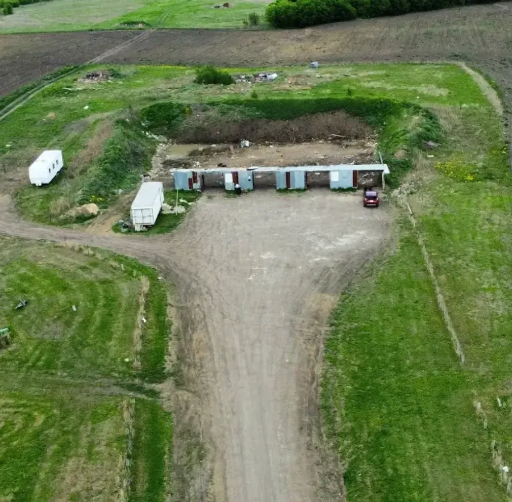 An aerial view of a farm with a dirt road going through it.