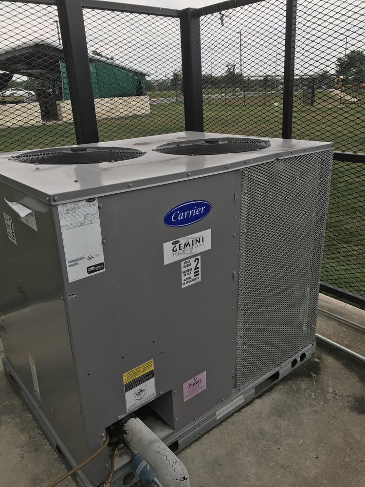 A carrier air conditioner is sitting on top of a concrete floor.