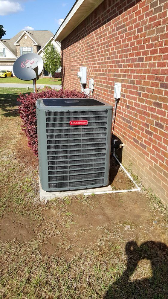 An air conditioner is sitting on the side of a brick building.