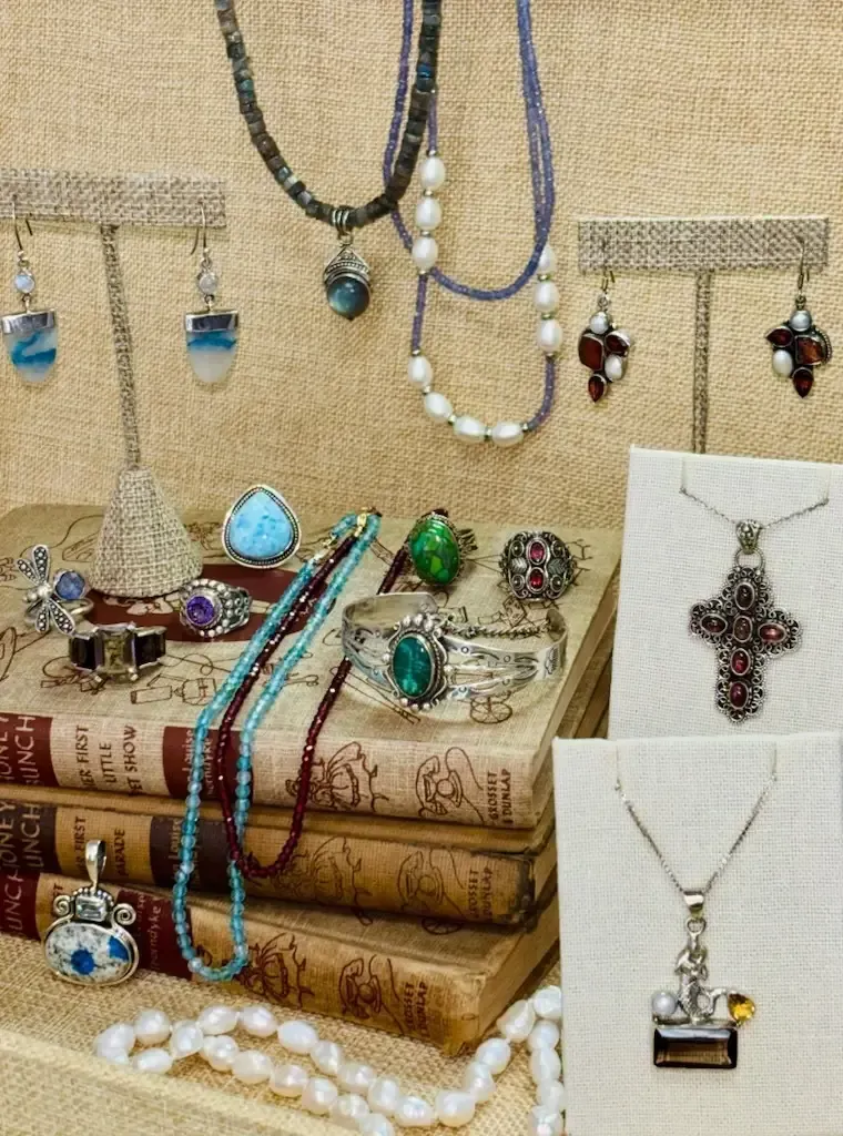 A collection of various jewelry, including necklaces, earrings, rings, and bracelets, displayed on stacked vintage books.