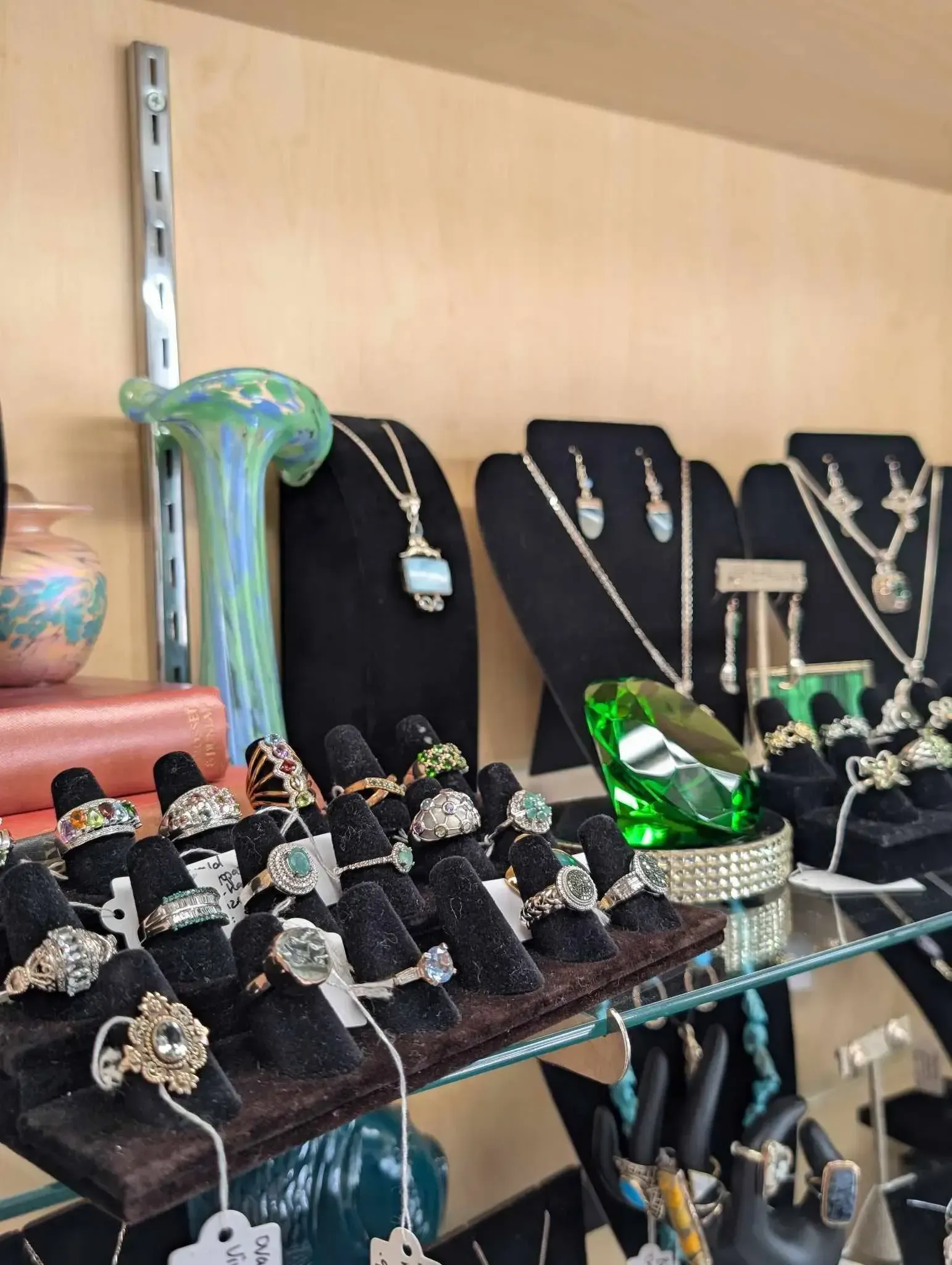A display case featuring various jewelry items, including multiple rings, necklaces on stands, and a green decorative stone.