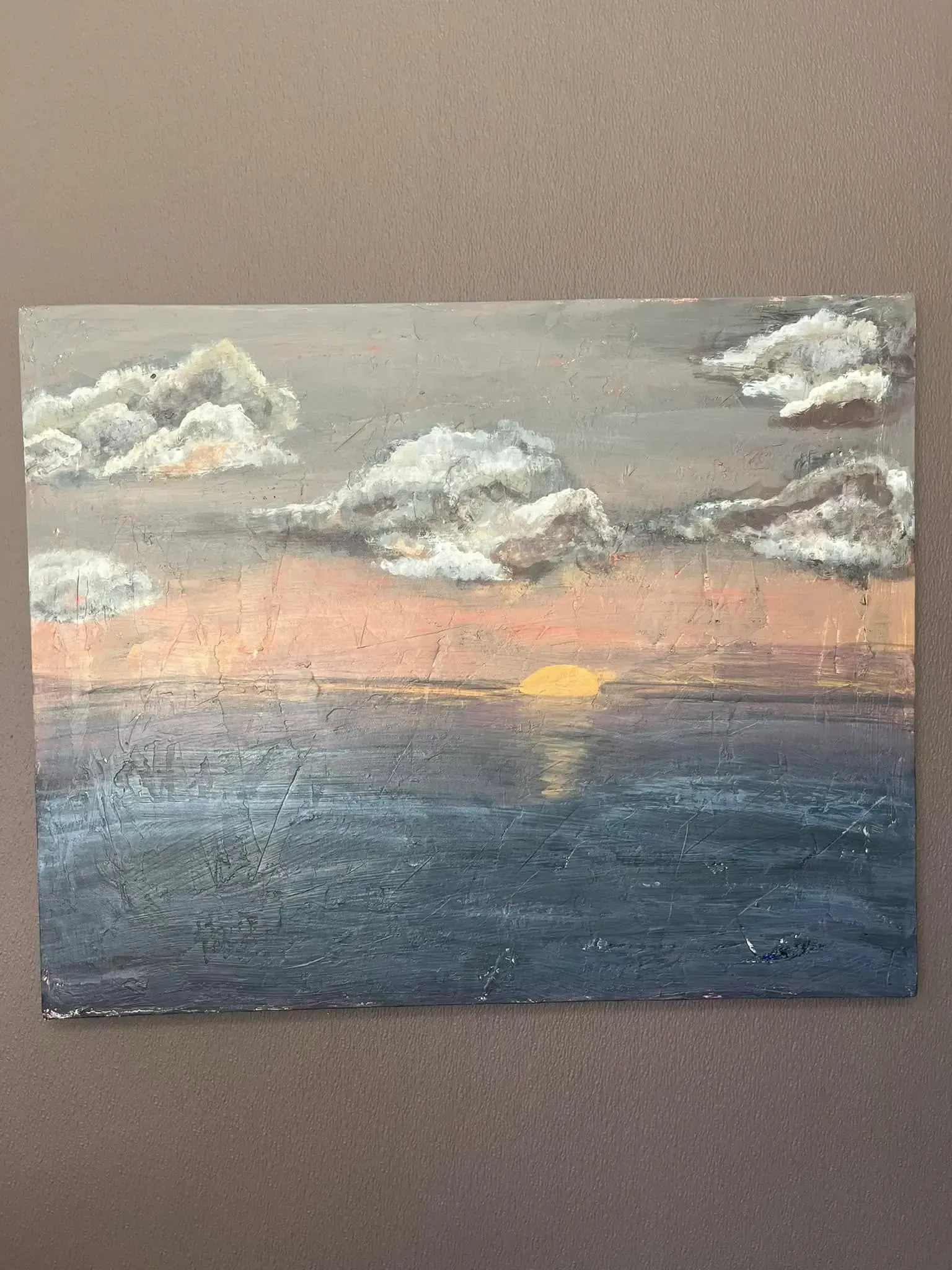 An oil painting shows a sunset over a dark blue sea, with fluffy clouds beneath a gray sky.