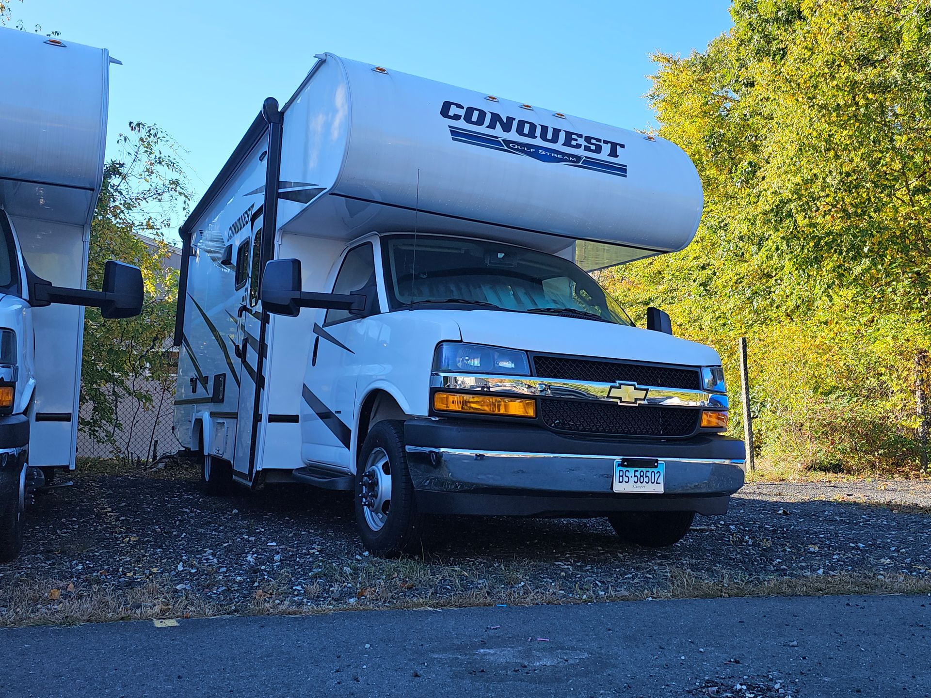 A white rv is parked next to another rv
