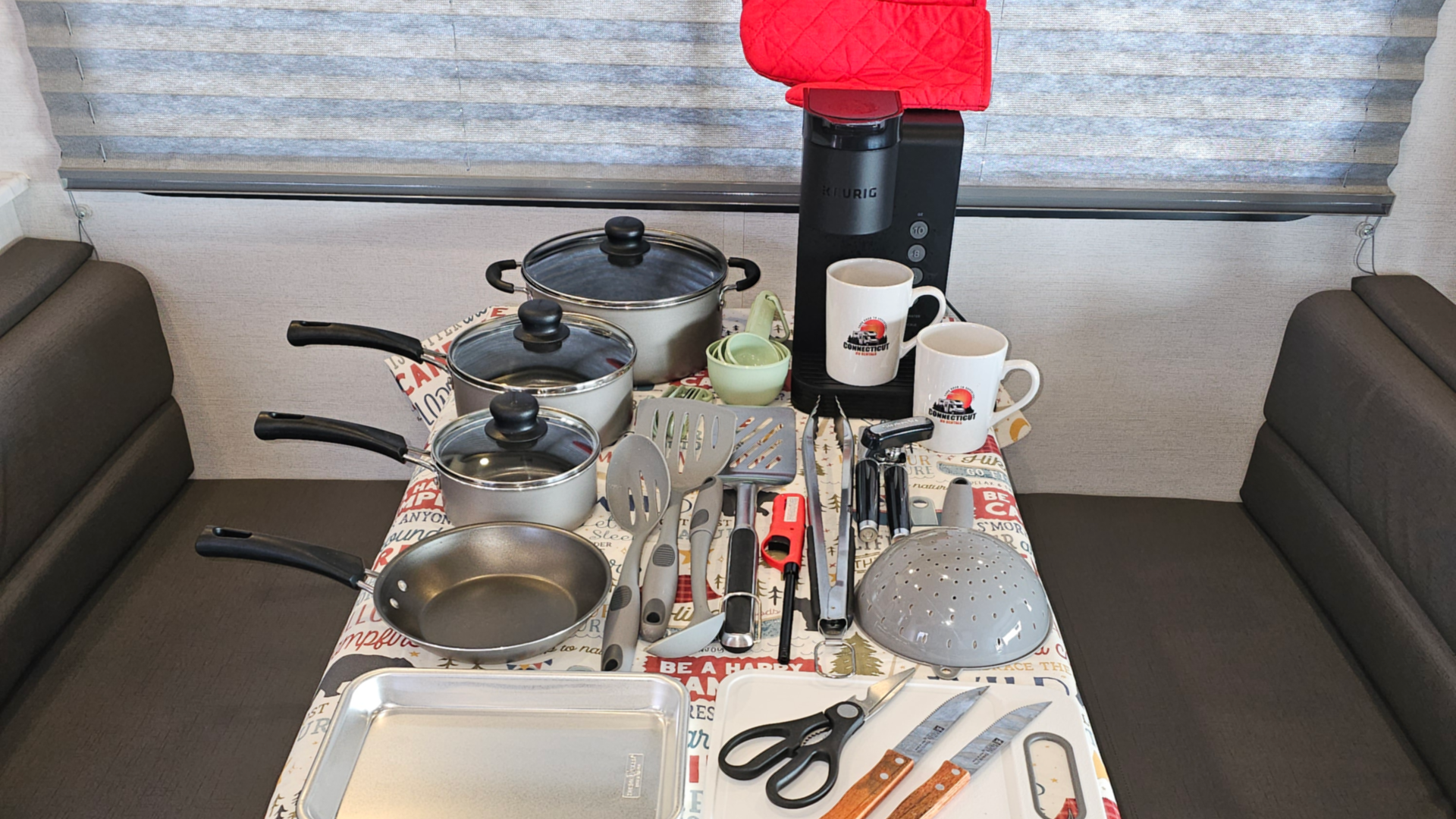 A table with pots, pans, cooking utensils, coffee maker and other kitchen amenities.