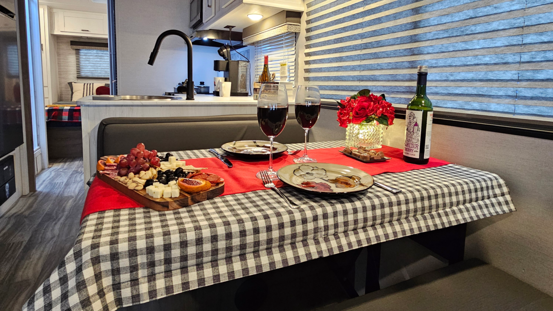 A table with plates , glasses of wine , and a bottle of wine on it.