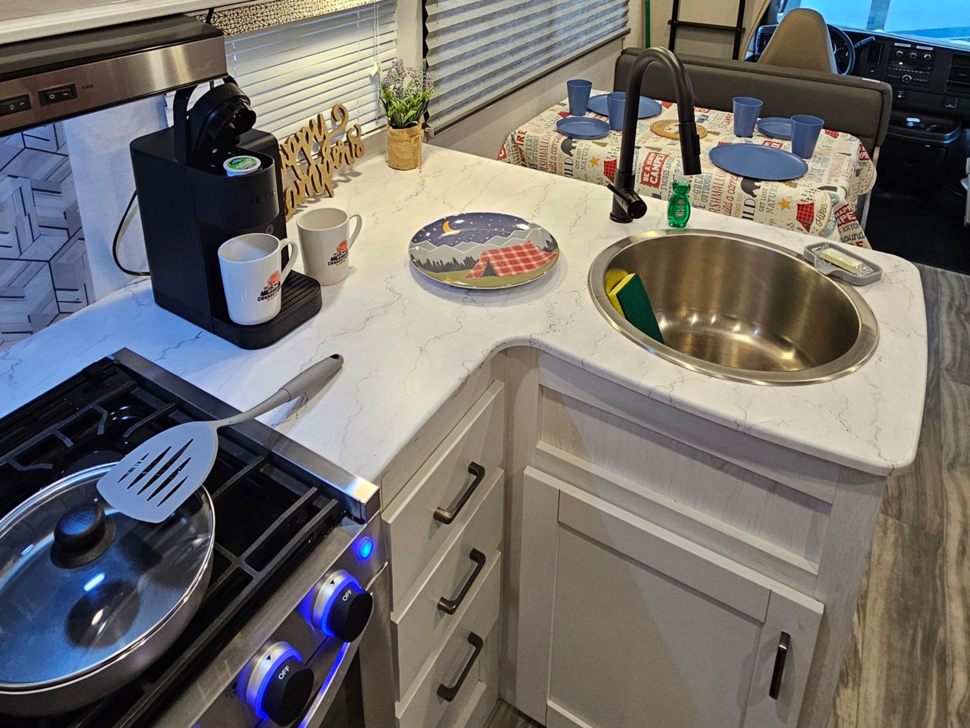 A kitchen in an RV with a sink , stove and microwave.