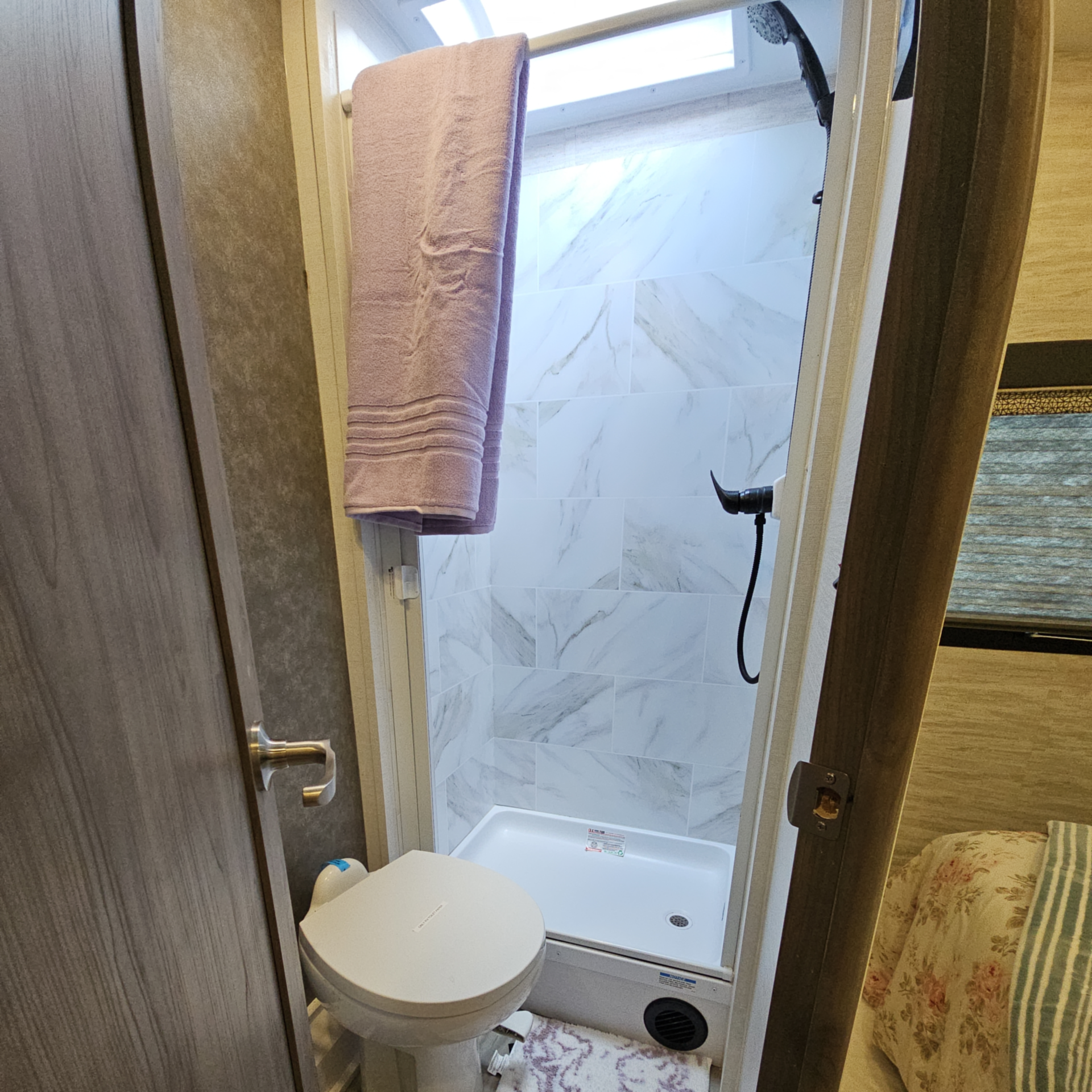 A bathroom with a toilet , sink , mirror and skylight.