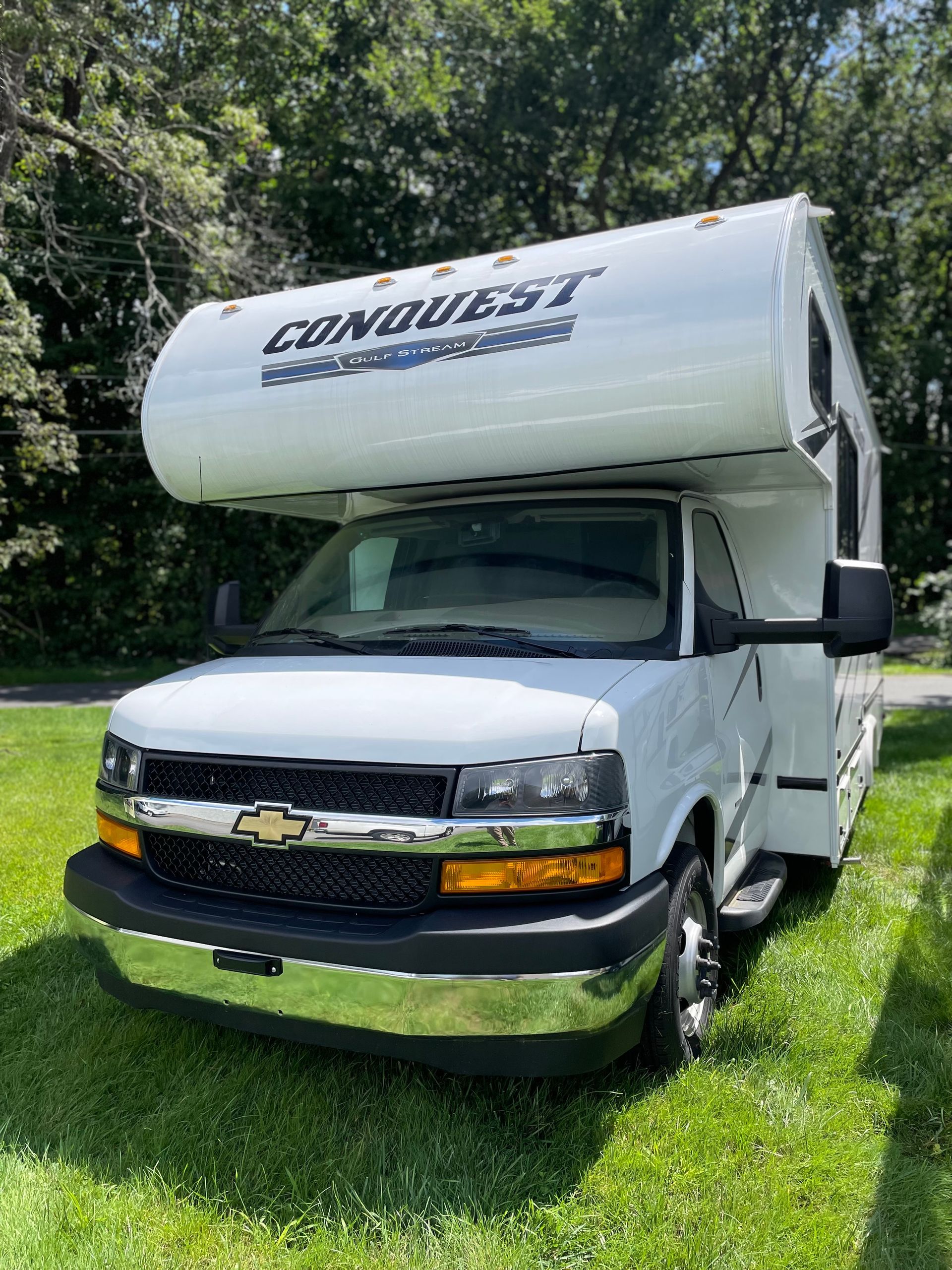 A white rv is parked in a grassy field.