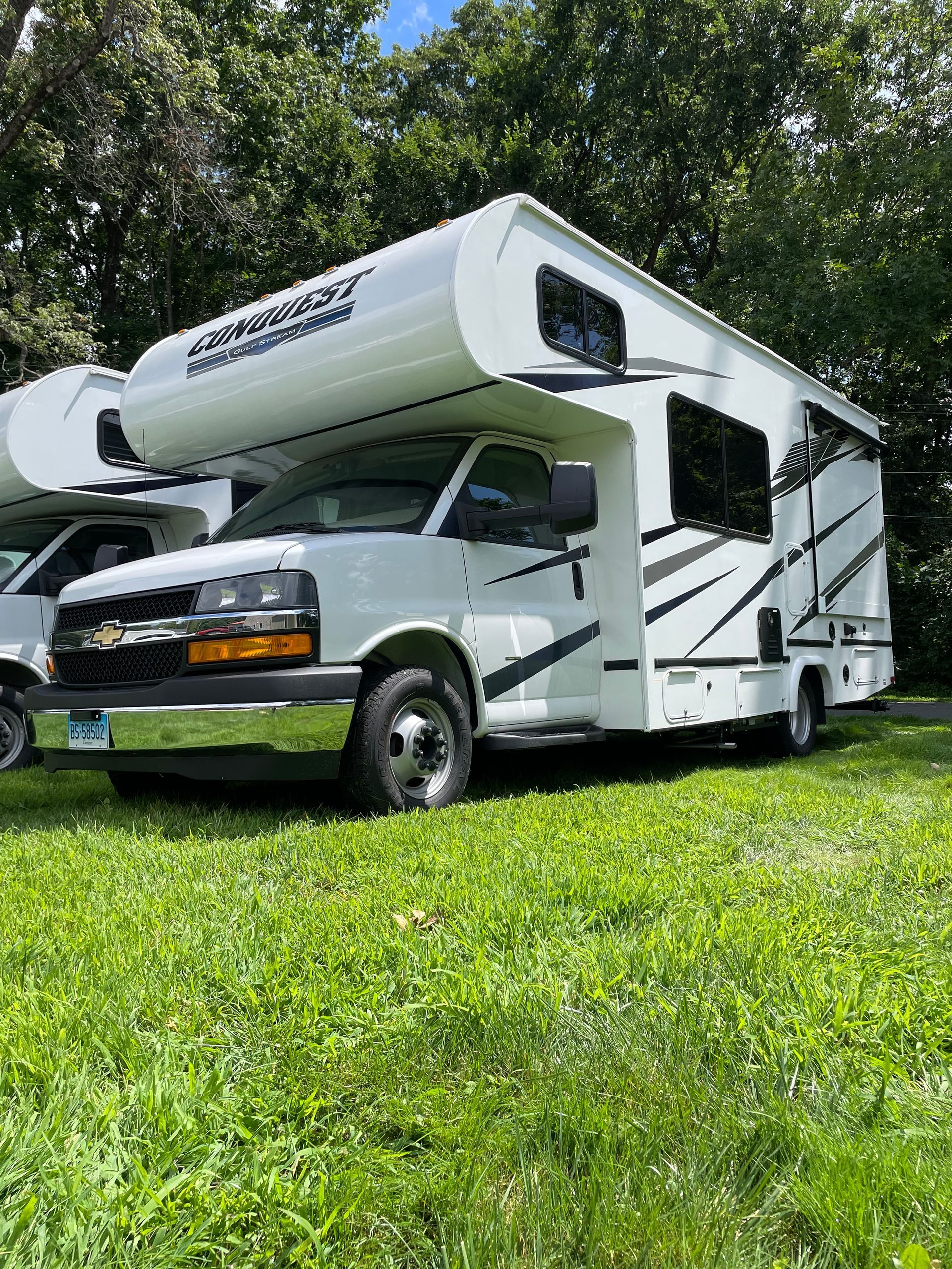 A white rv is parked in a grassy field.