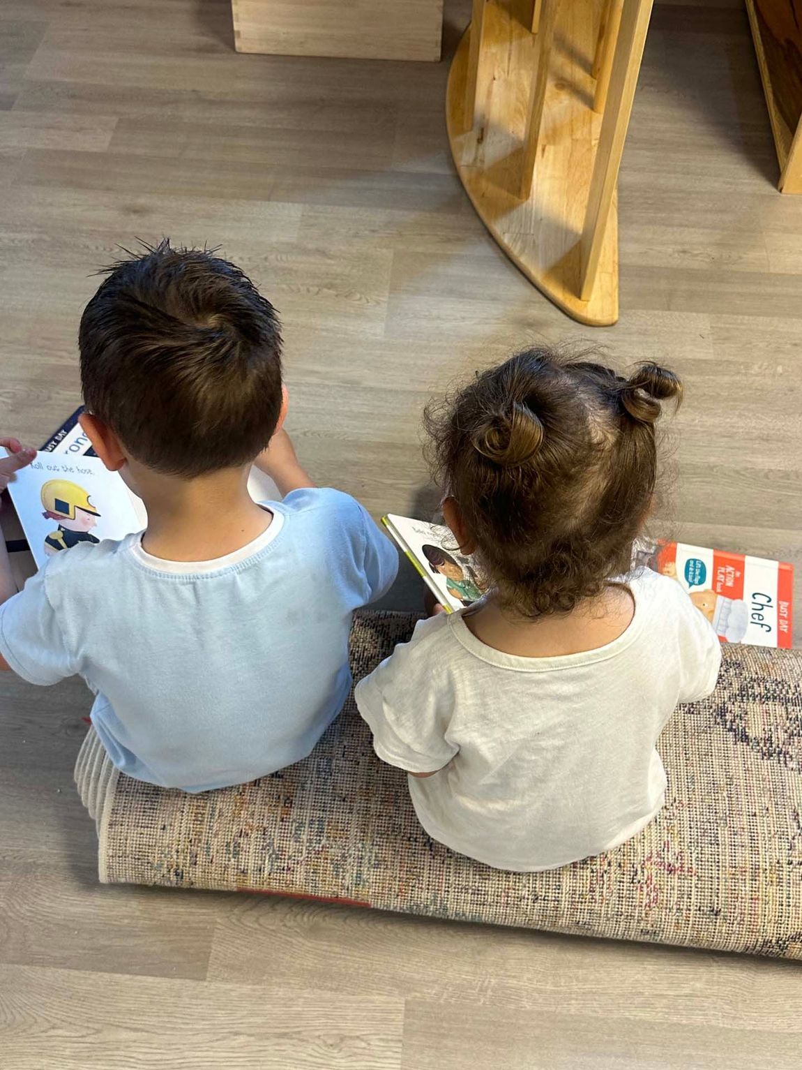 A boy and a girl are sitting on the floor reading books.