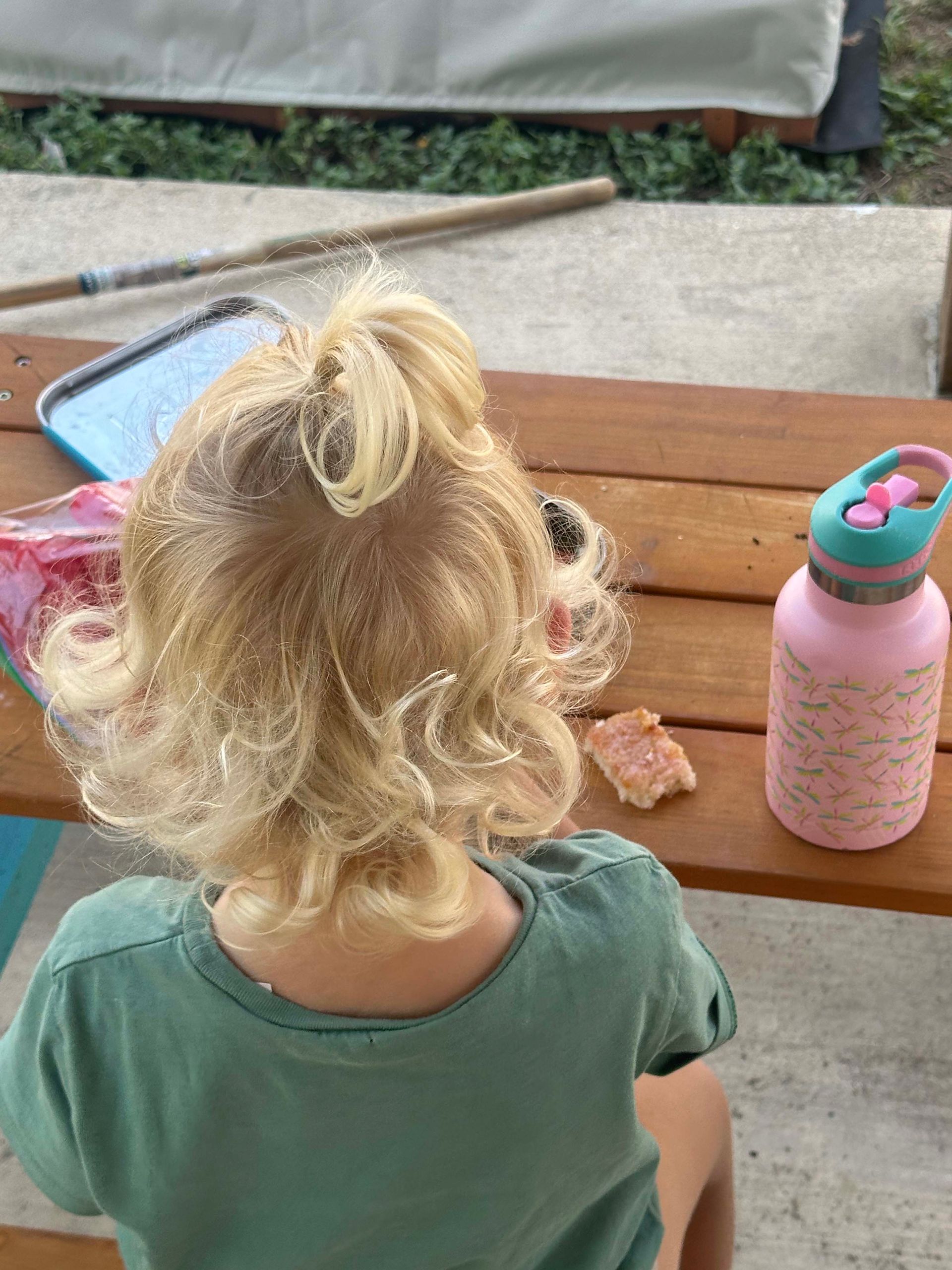 A little girl is sitting at a picnic table with a water bottle.