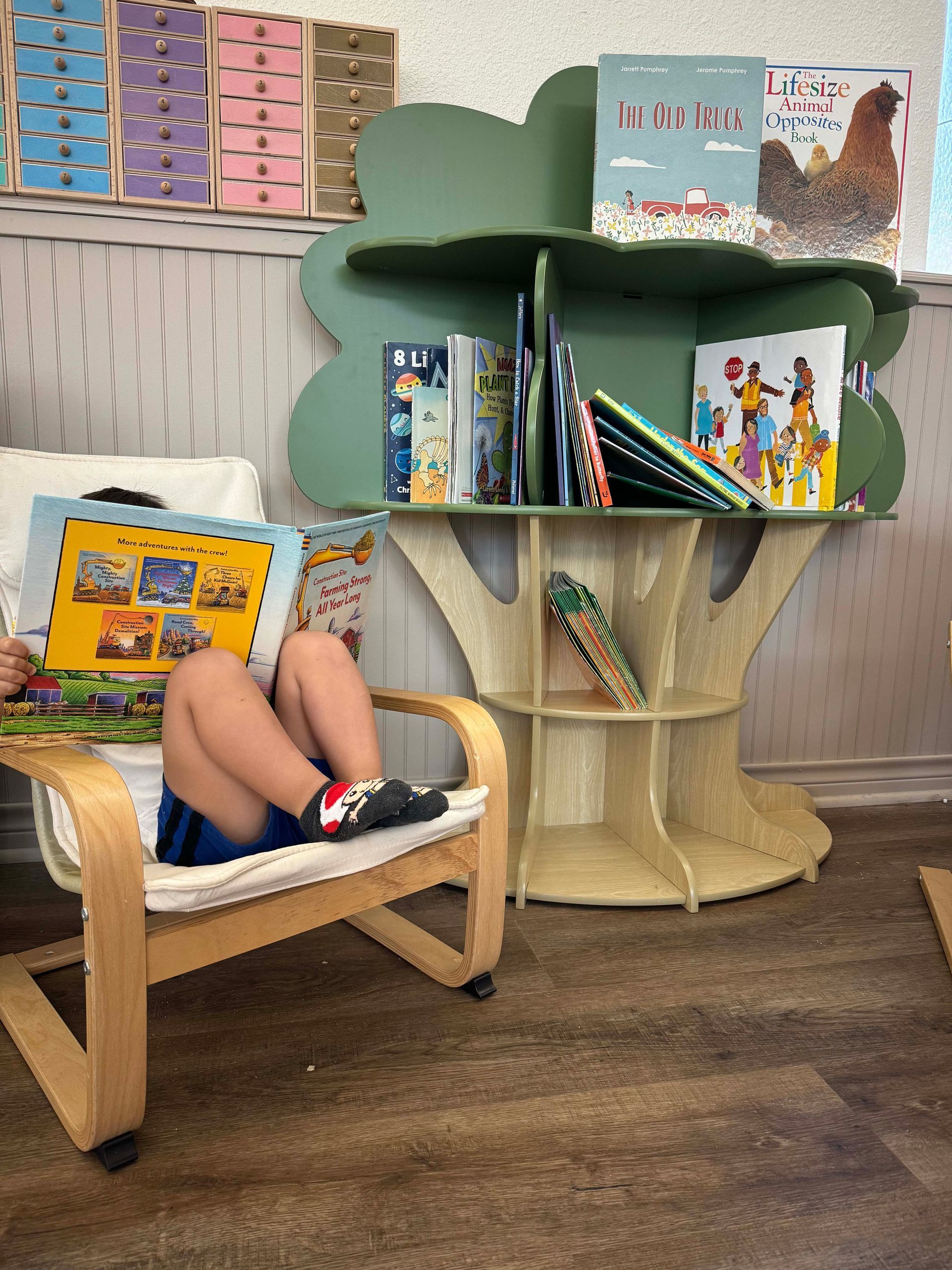 A child is sitting in a chair reading a book