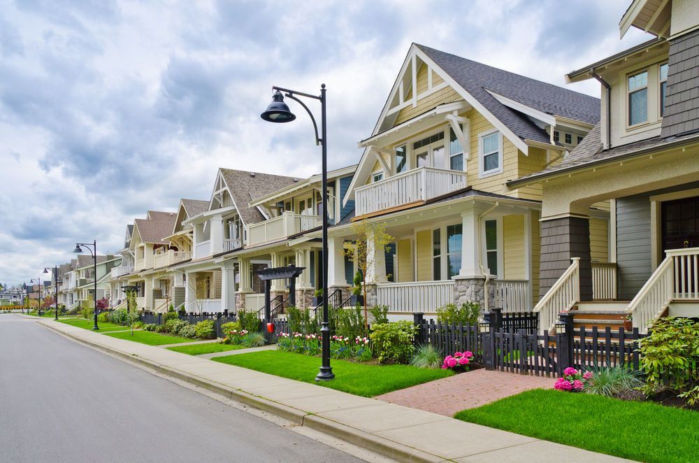 Row of colorful houses with green lawns and a cloudy sky.