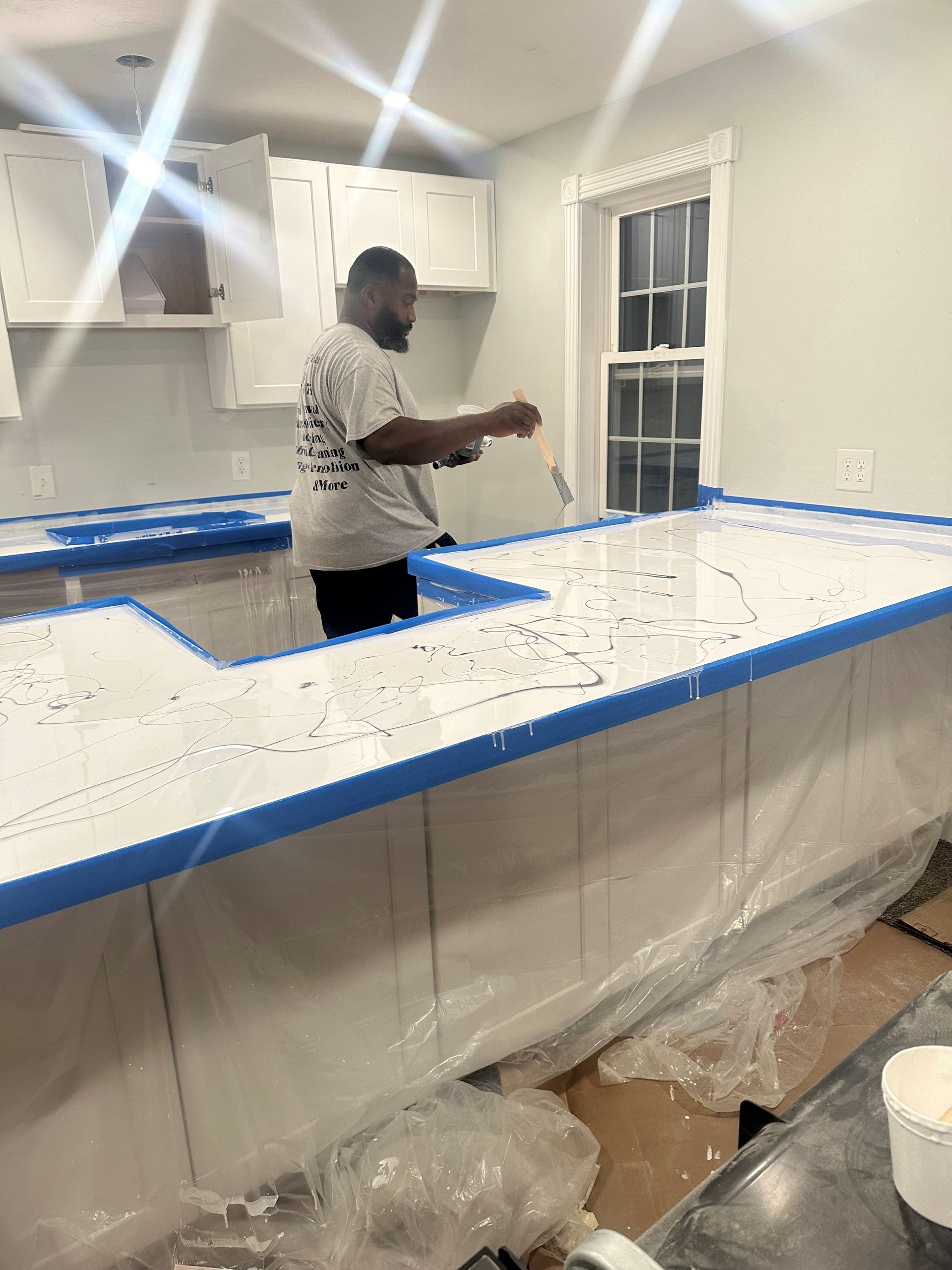 A man is painting a kitchen counter with a brush.