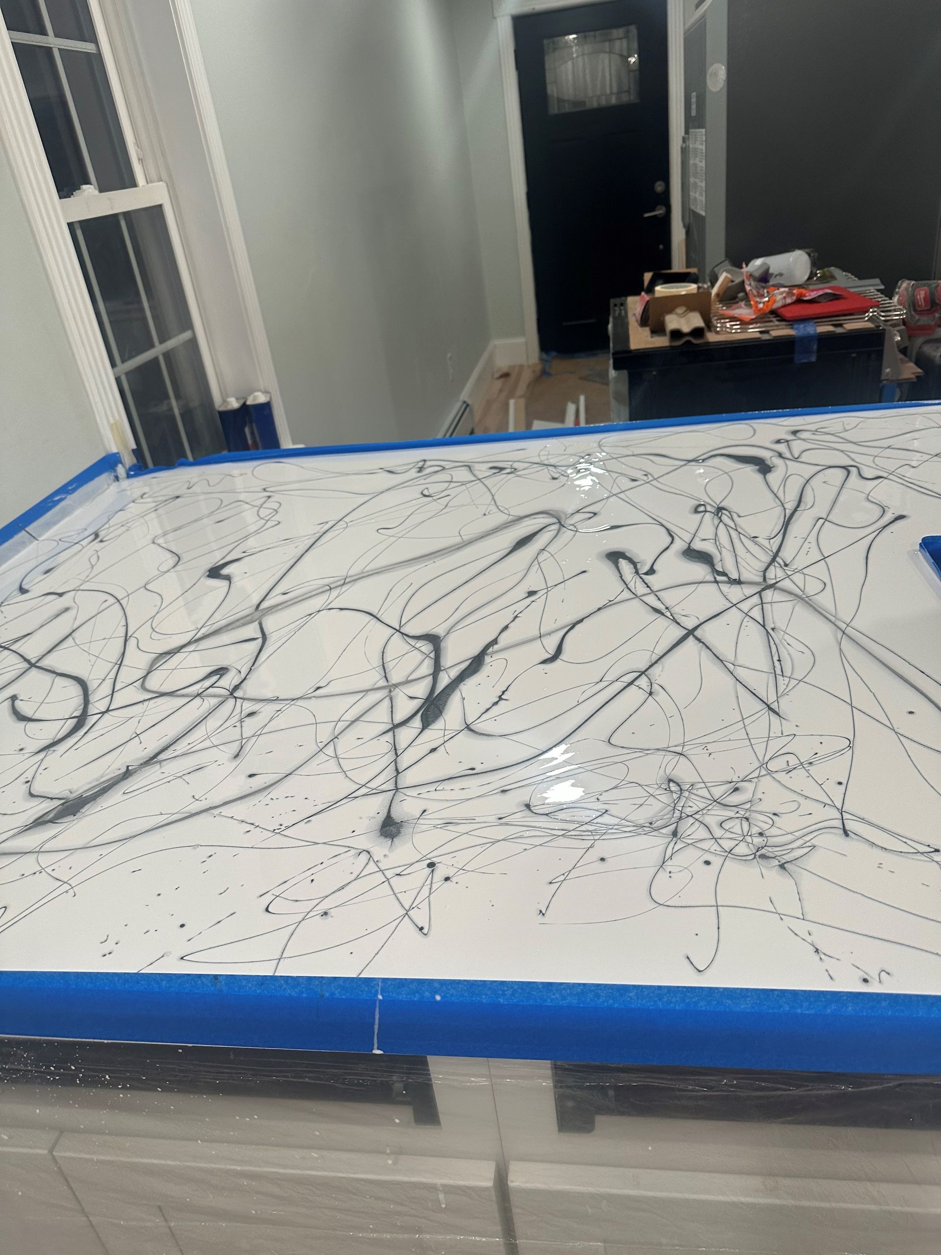 A white table with black lines on it is covered in blue tape.