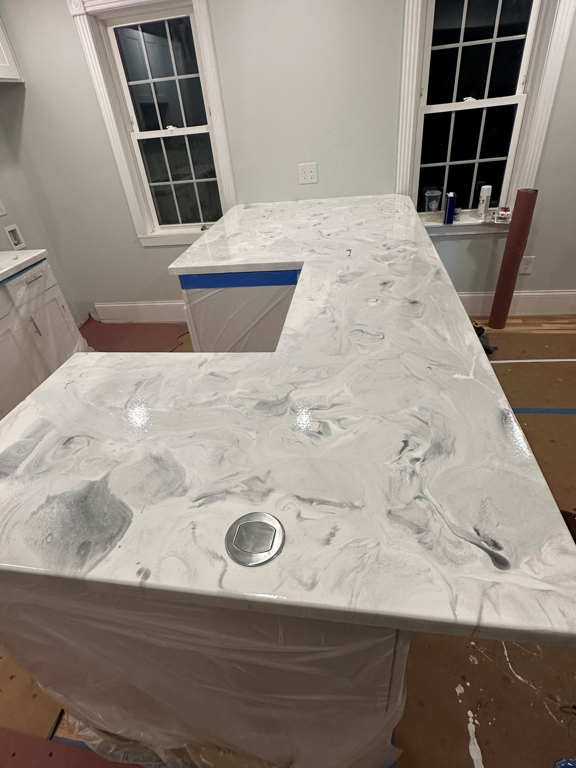 A white counter top is sitting in a kitchen next to a window.