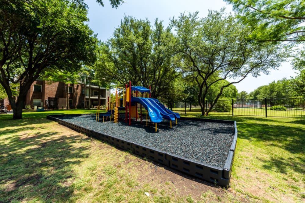 A playground surrounded by trees at Marquis at Legacy in Plano, TX.