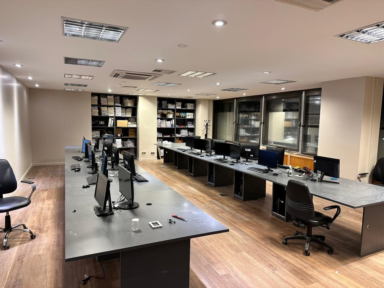 Una oficina grande con muchos escritorios, sillas y computadoras.