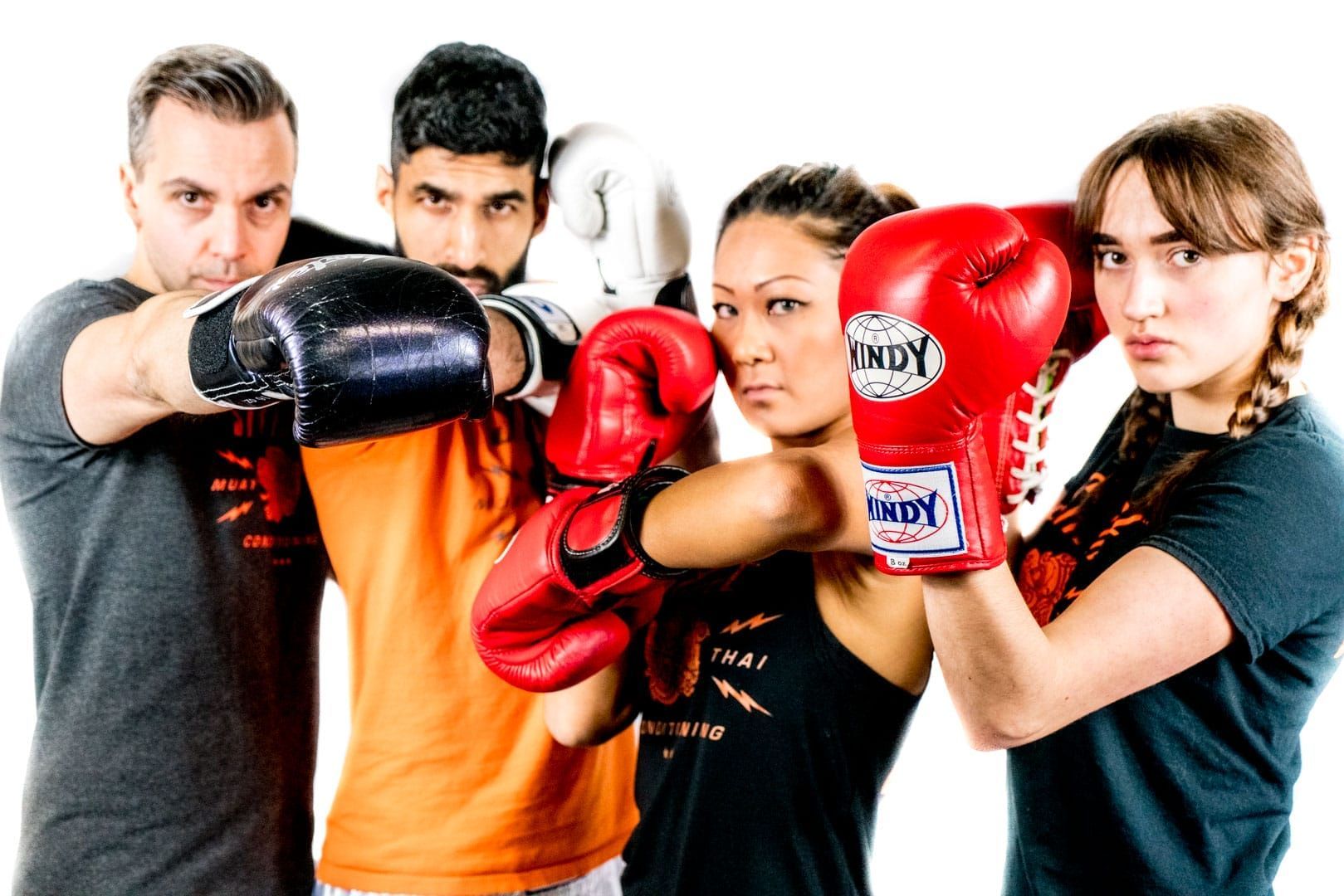 Four people in boxing gloves: two men, two women, striking a boxing pose.