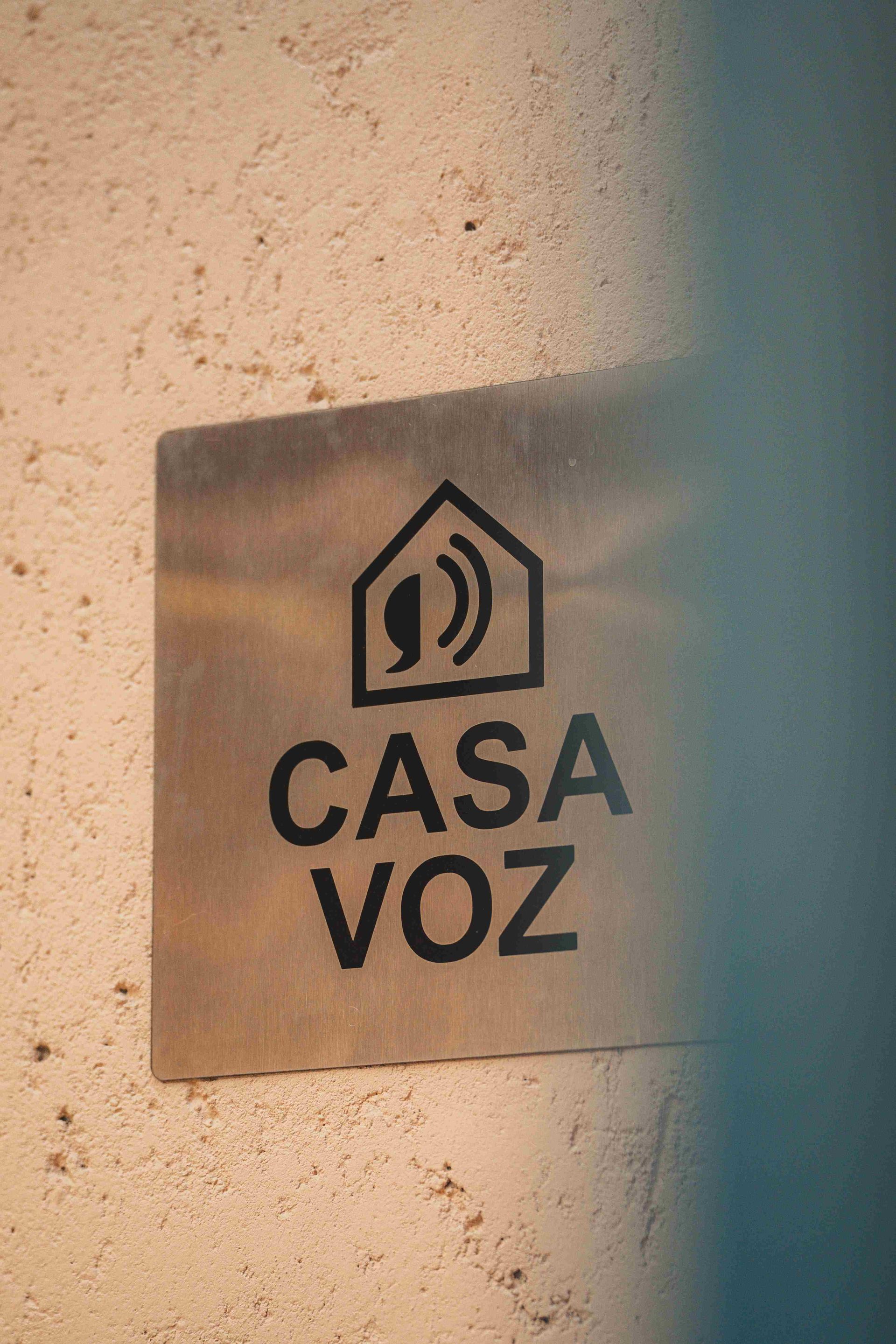 Uma placa metálica quadrada em uma parede texturizada exibe a inscrição 