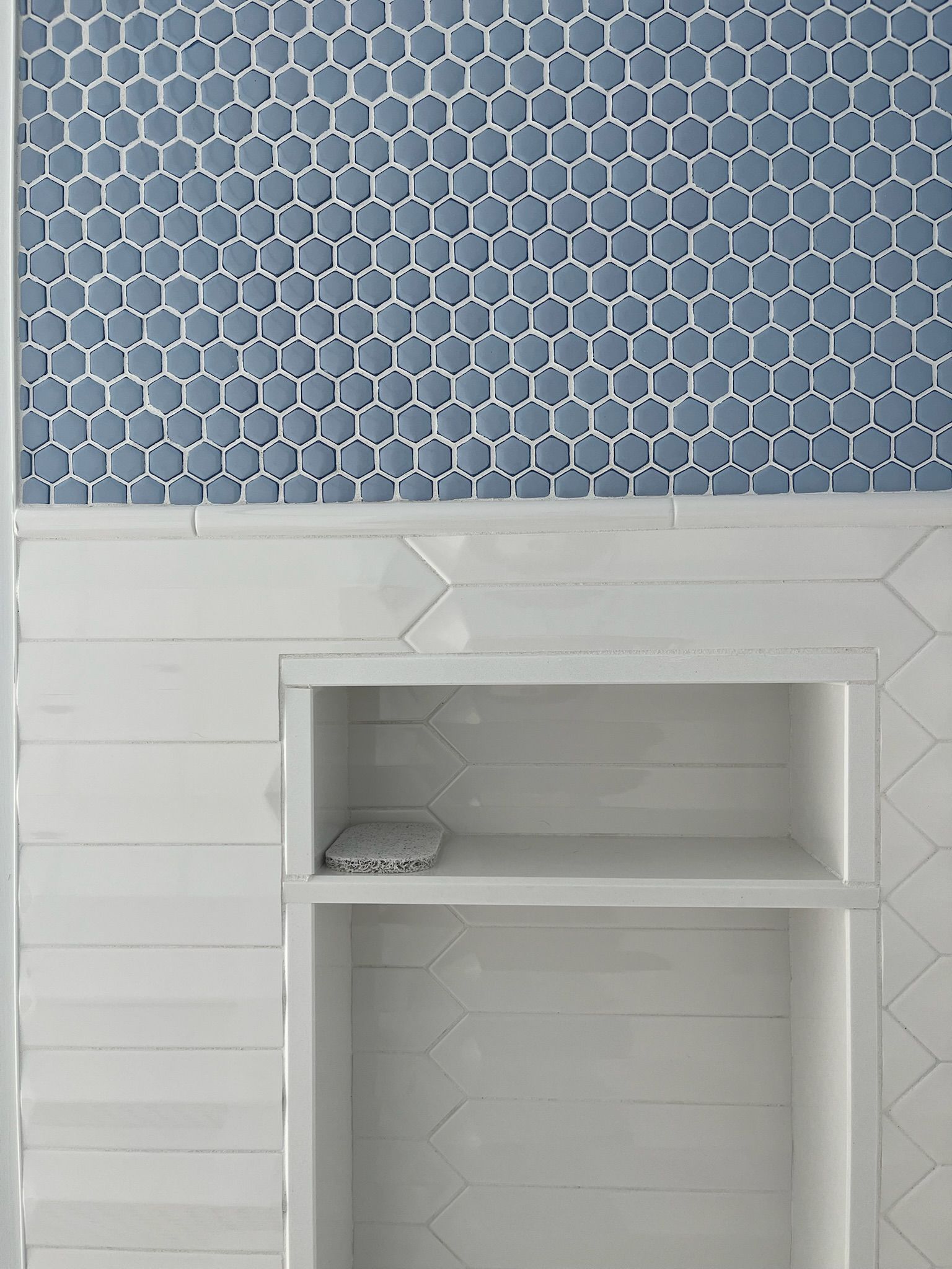 A person points at carpet samples in various neutral colors, displayed on a white board.