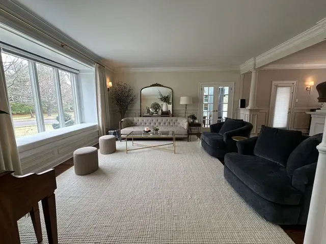 Living room with a large window, a sofa, chairs, and a neutral-colored rug.