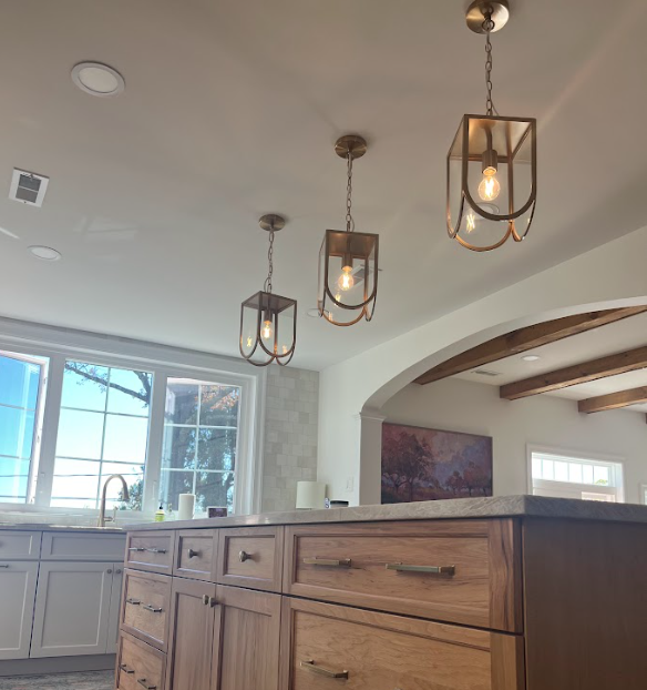 Modern living room with TV, beige couch, wood floors, and recessed lighting.