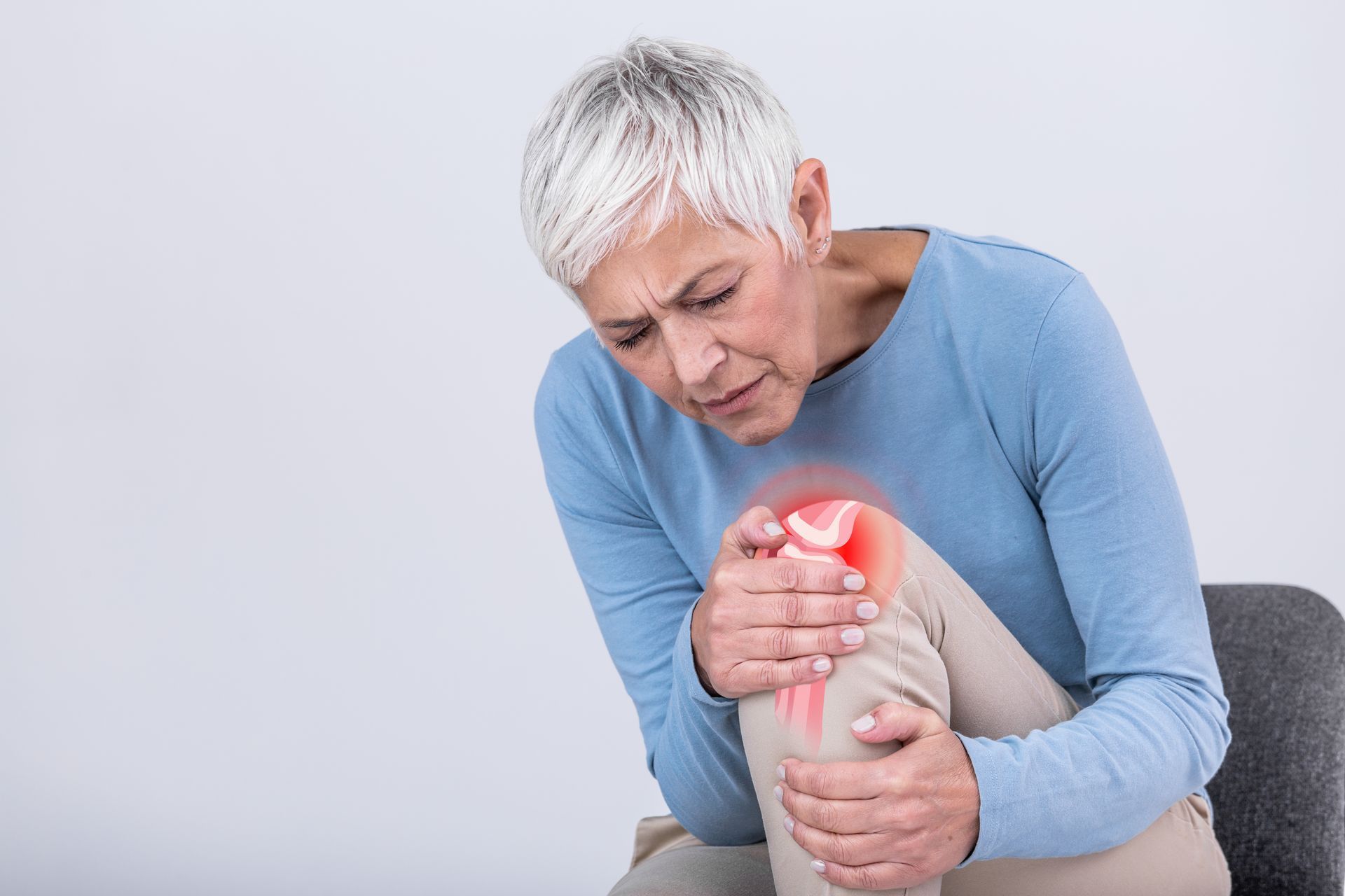 A Person with Gray Hair Wearing a Blue Shirt Sits Holding Their Knee — Mitchell Playford & Radburn Solicitors in Grafton, NSW