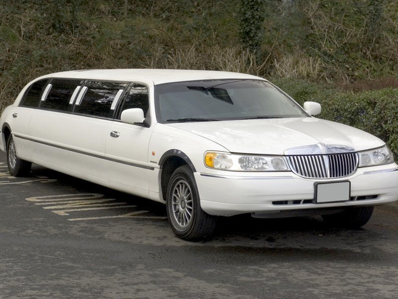 A white limousine is parked in a parking lot.
