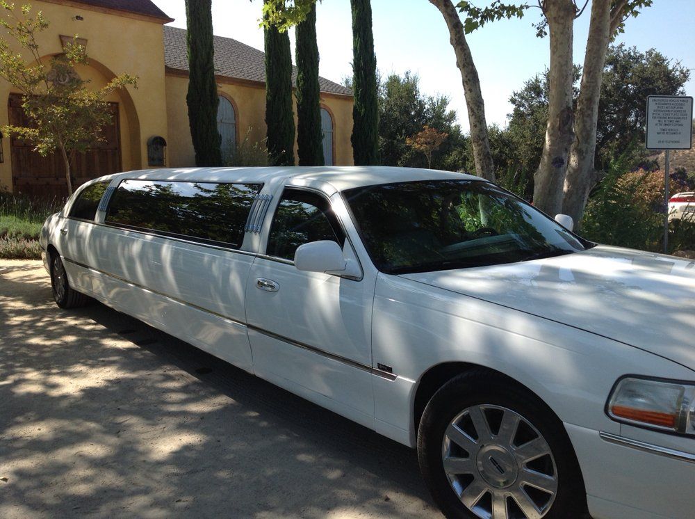A white limousine is parked in front of a church