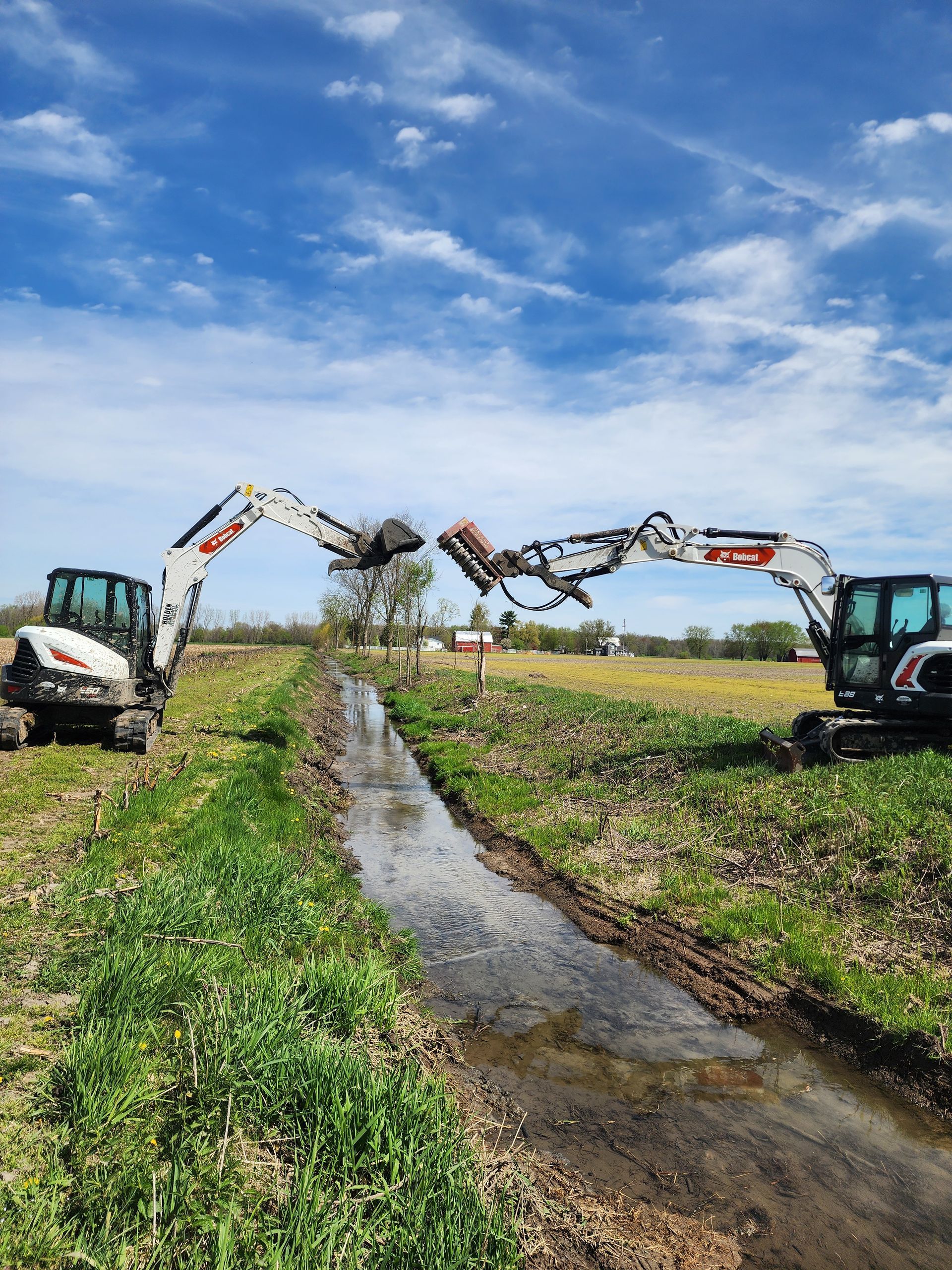 Man using a rake to smooth wet concrete in a sidewalk repair. Debris and caution tape are nearby.