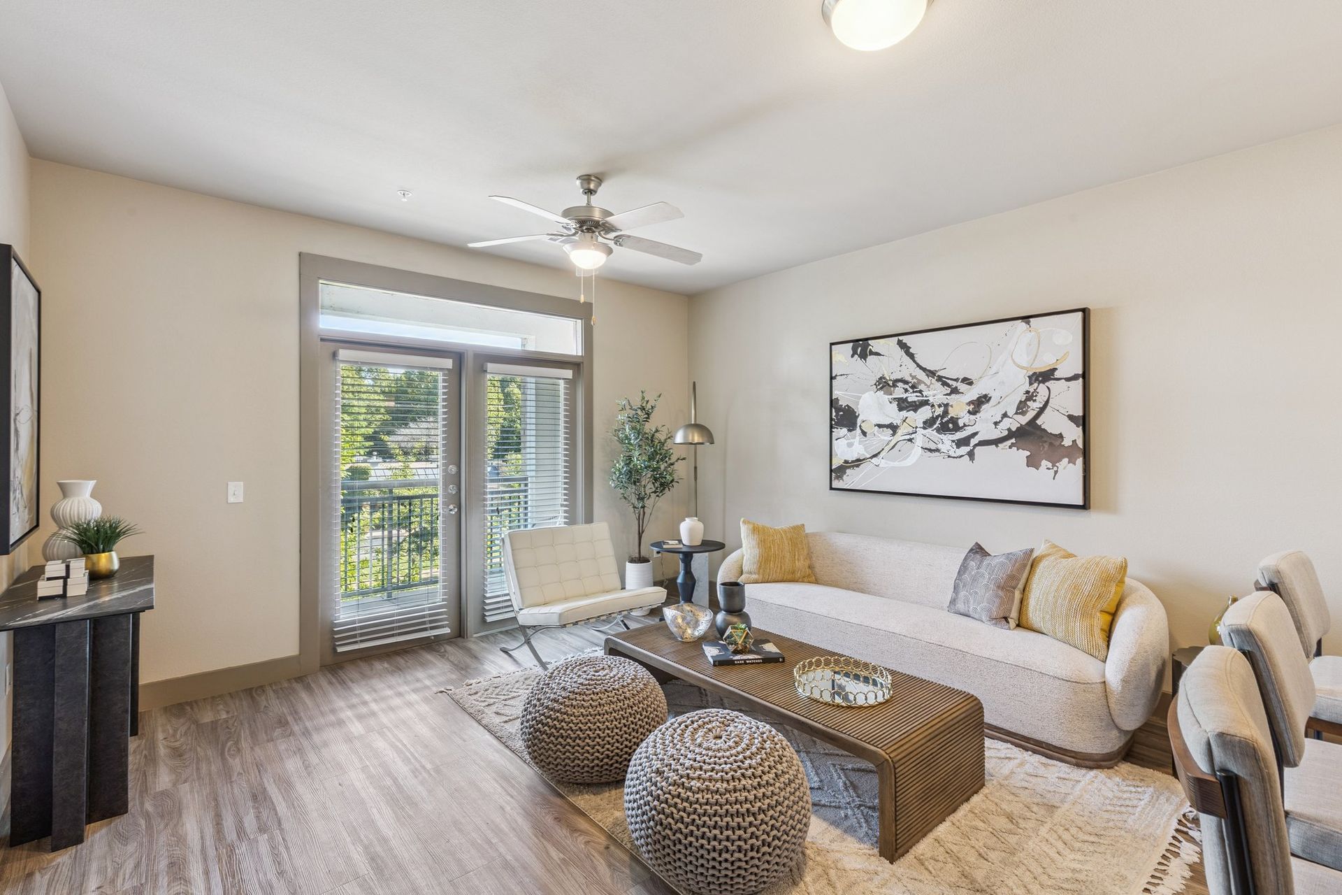 Living room with sofa, chairs, rug, coffee table, and balcony access.