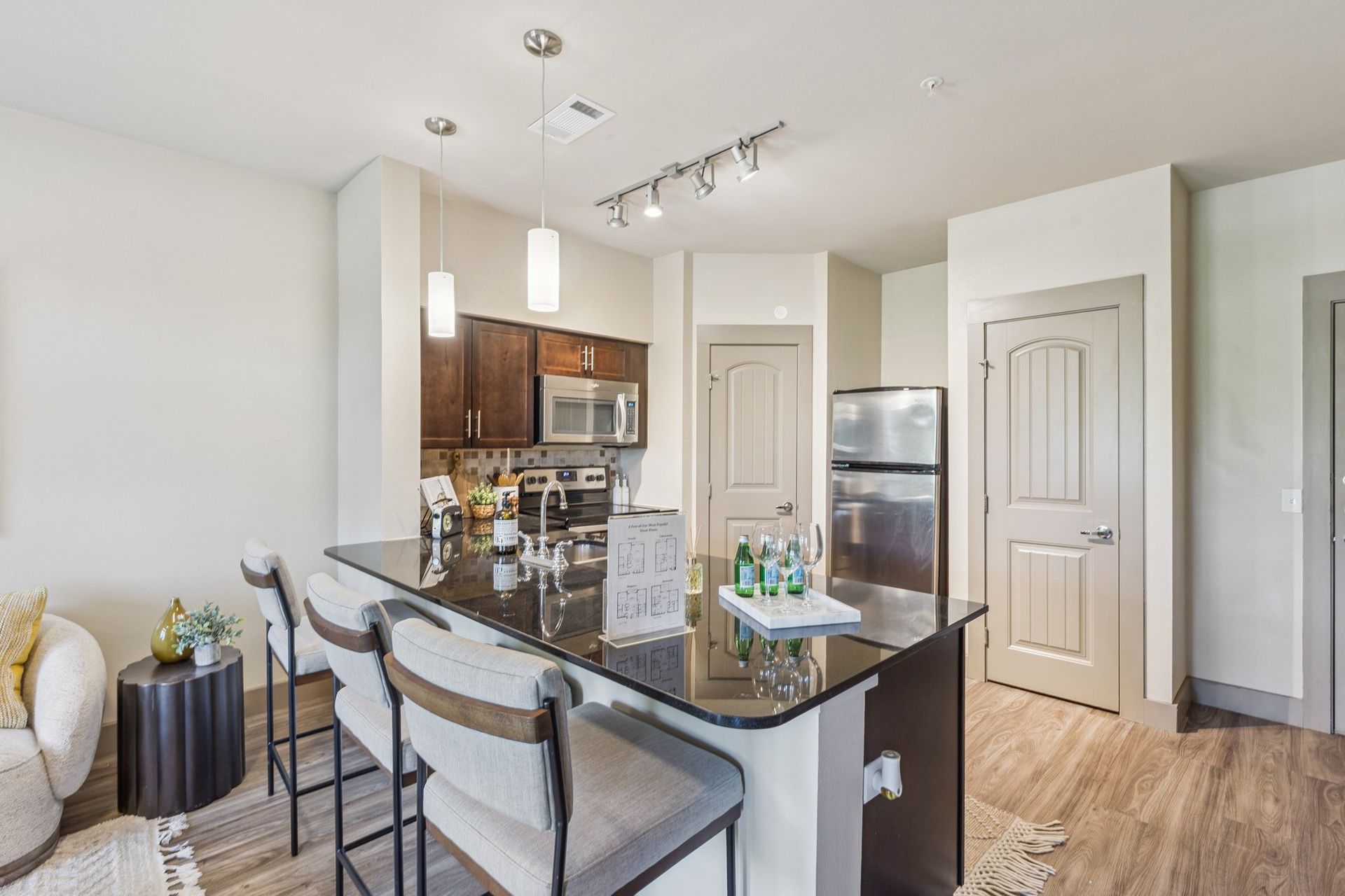 Kitchen with island, dark countertops, bar stools, and stainless steel appliances.