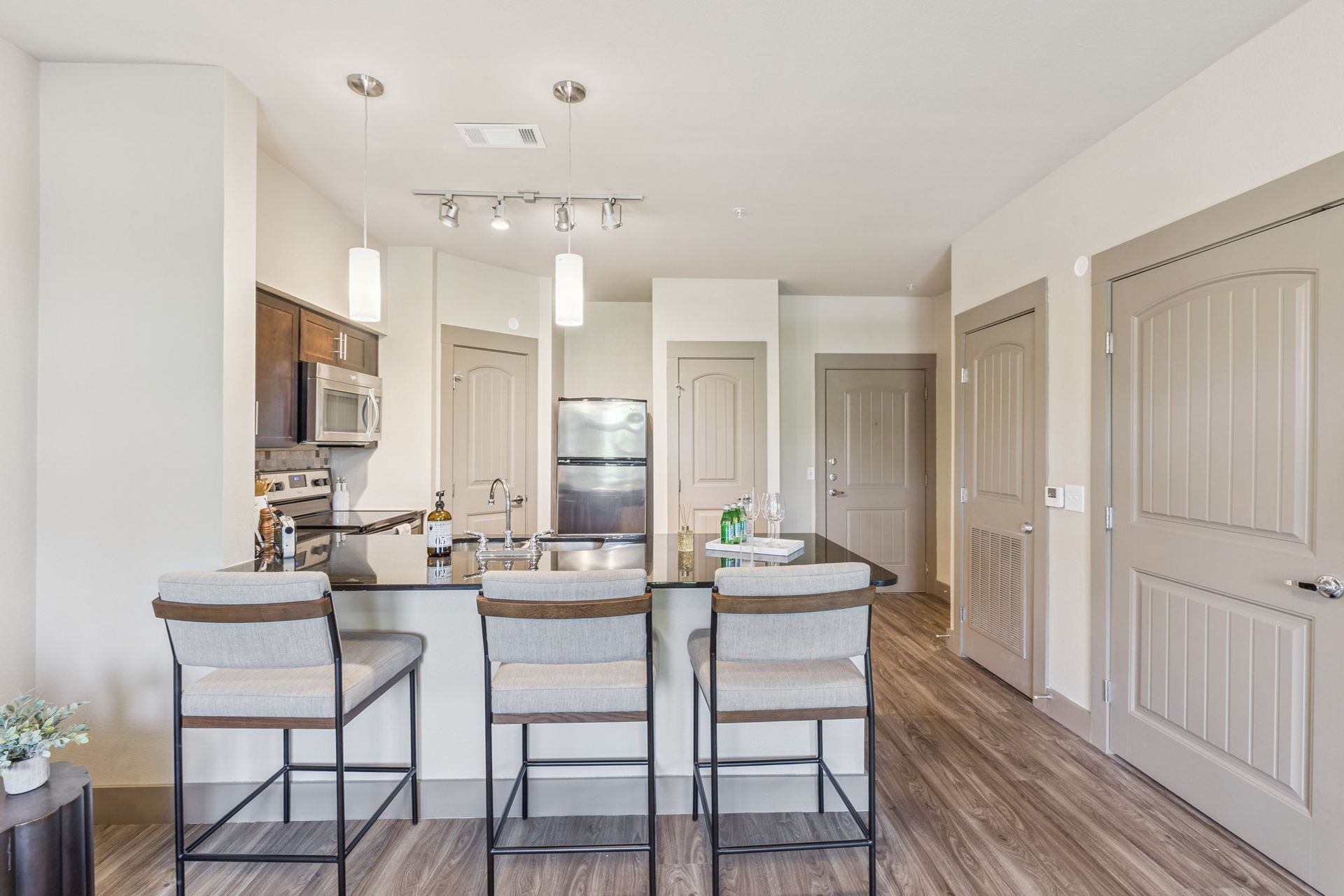 Modern kitchen with a black countertop island, bar stools, and stainless steel appliances.