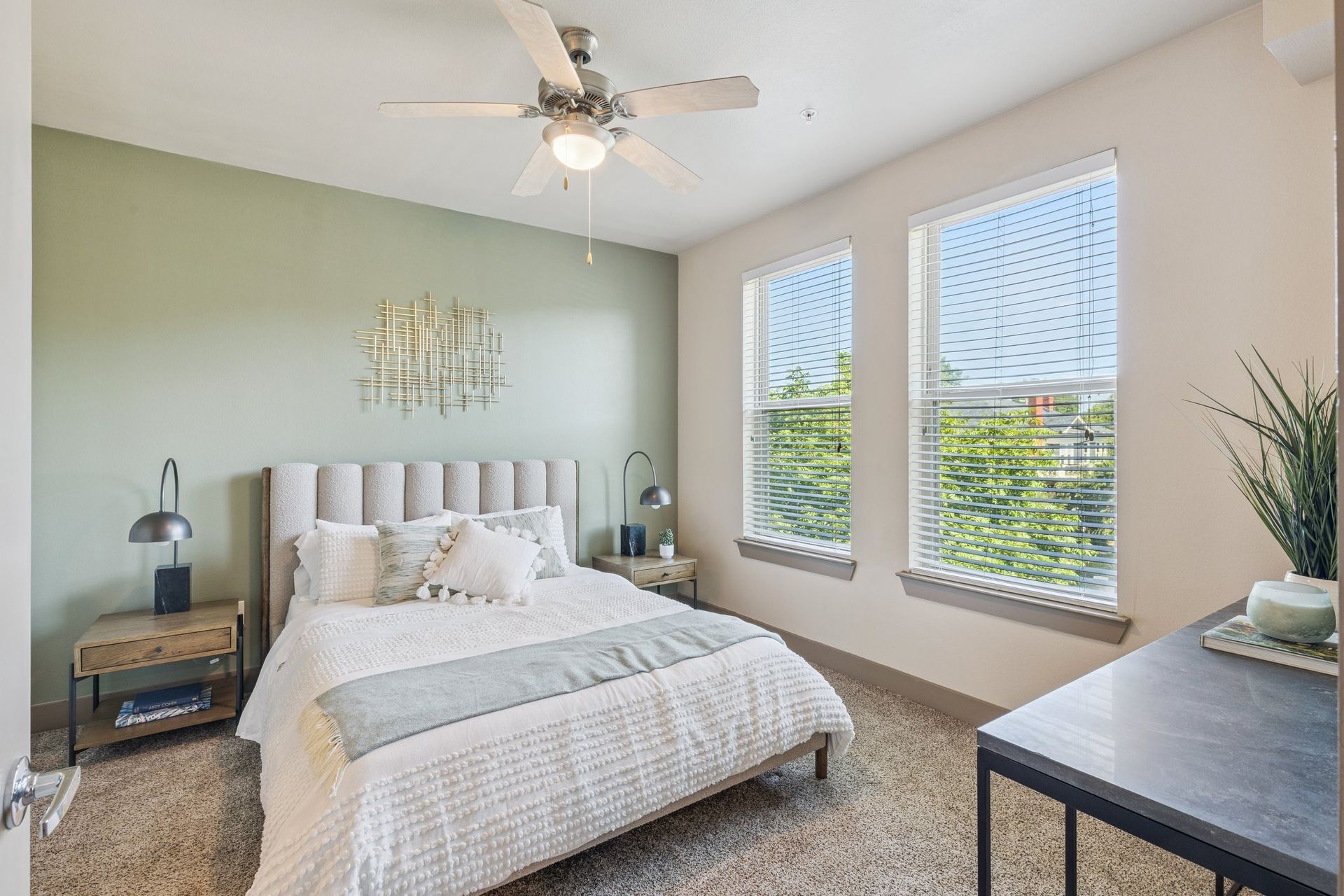 Bedroom with bed, nightstands, and windows; sage green accent wall.