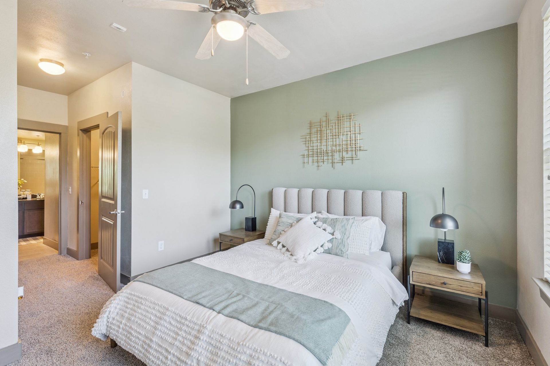 Bedroom with bed, nightstands, and mint green accent wall. Doorway to bathroom.