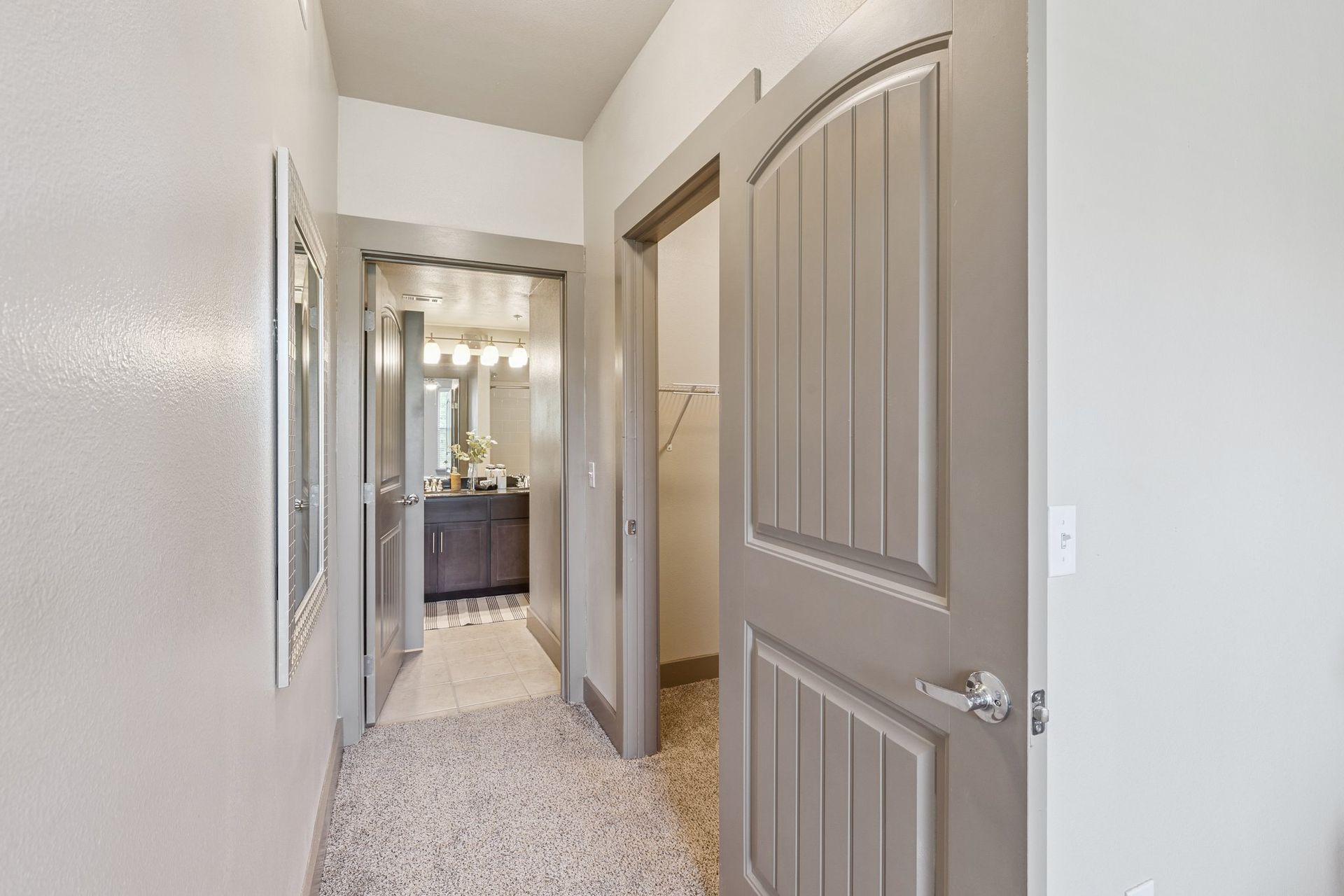 Hallway with doors leading to a bathroom and a closet, with a speckled floor and gray walls.