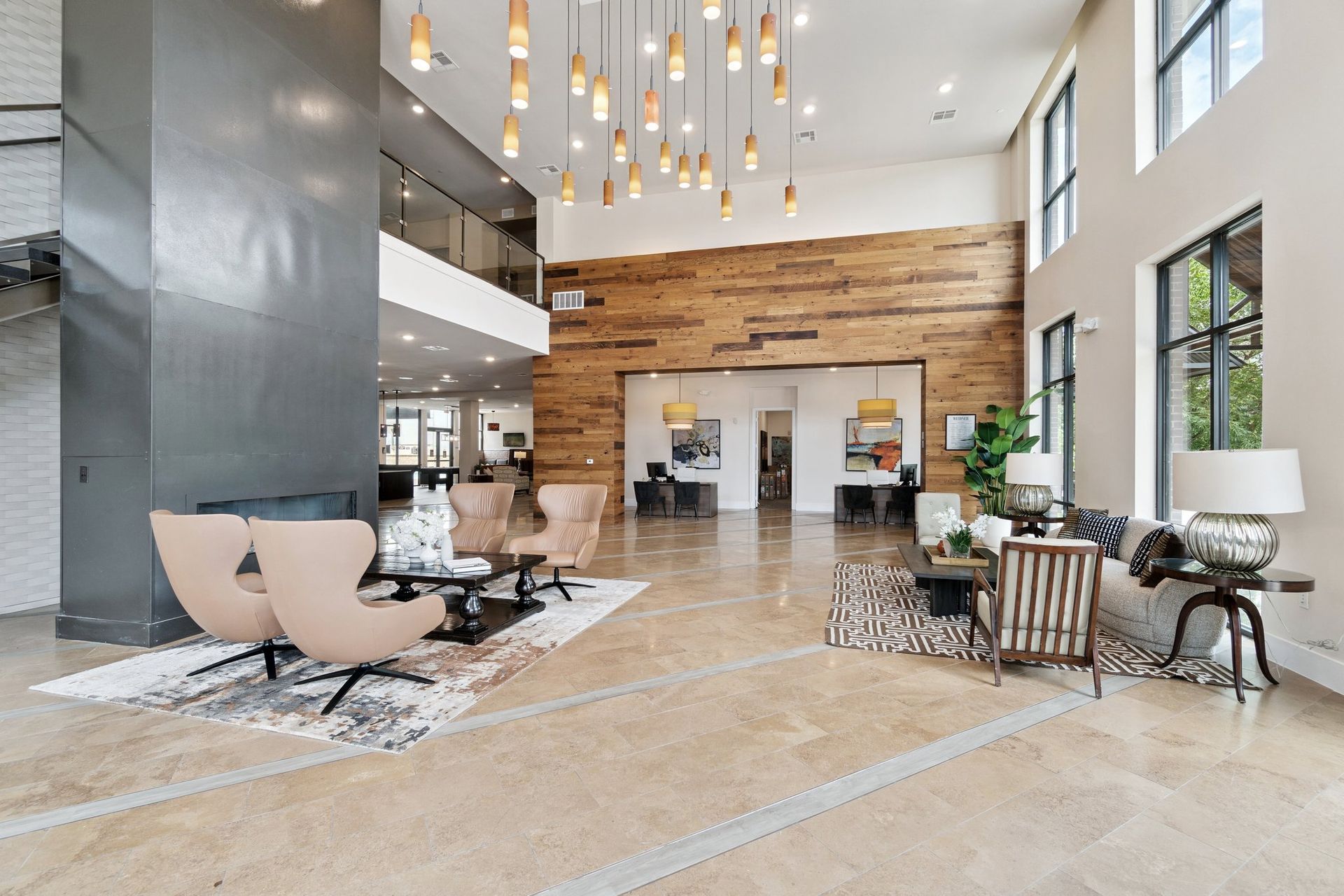 Lobby with seating, wood accent wall, hanging lights, and large windows.