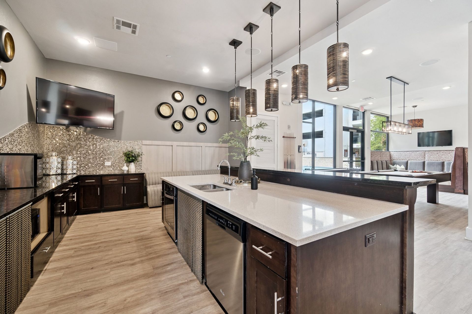 Modern kitchen with island, dark cabinets, stainless appliances, and pendant lights.