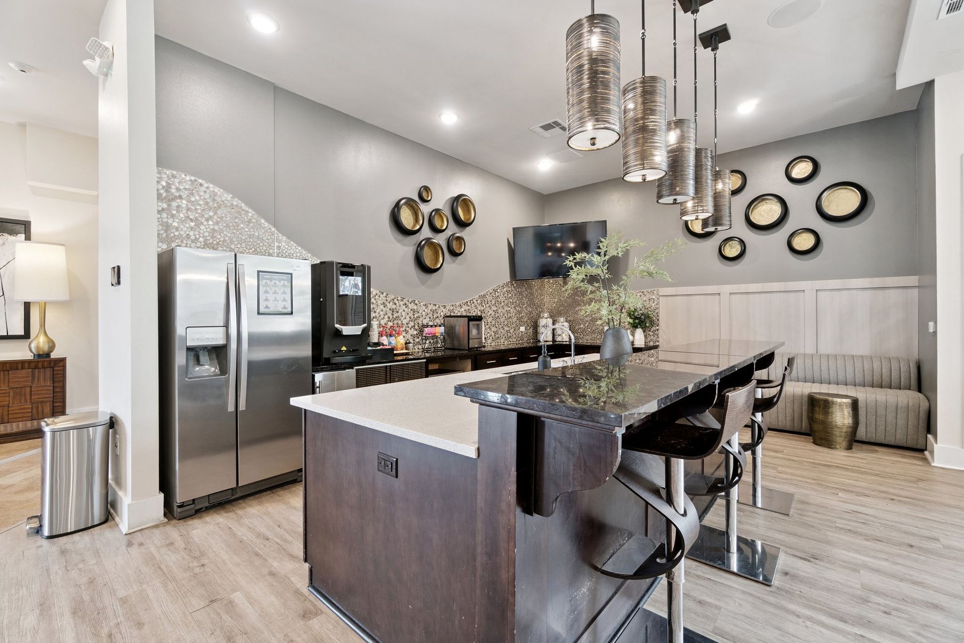 Modern kitchen area with stainless steel appliances, a dark countertop island, and pendant lights.