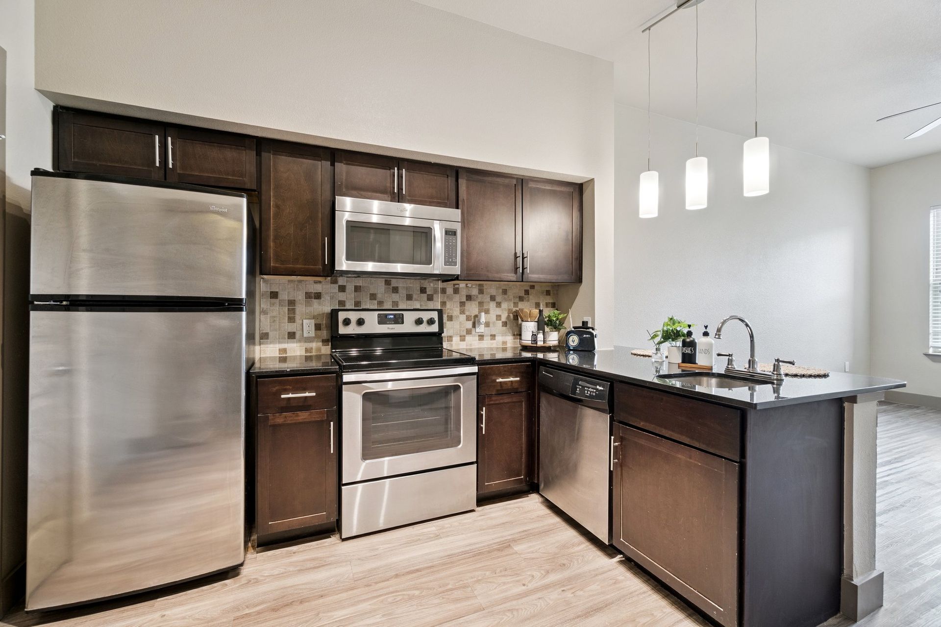 Modern kitchen with stainless steel appliances, dark cabinets, and a kitchen island with a sink.